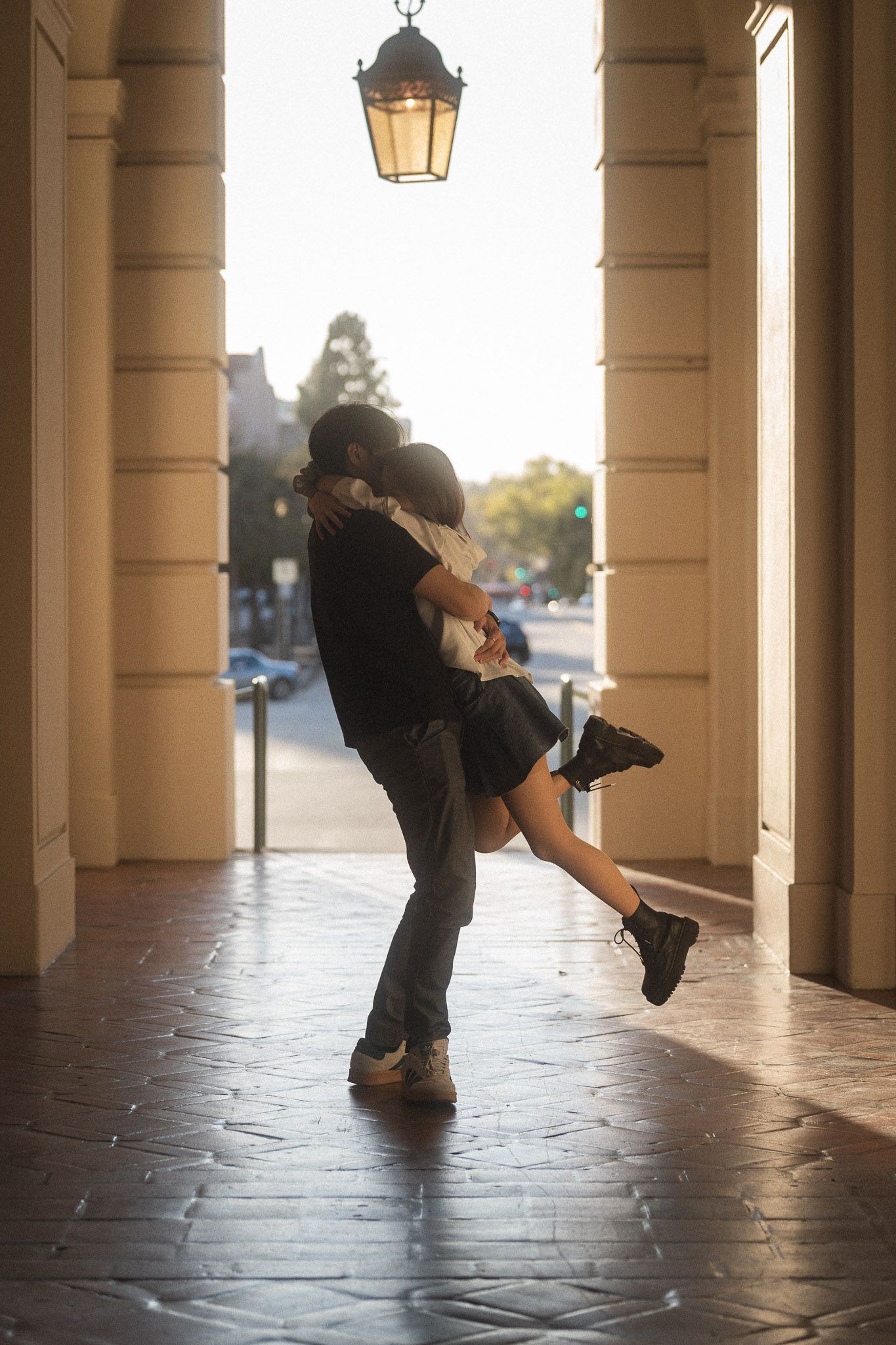 Warm cinematic portrait of couple hugging and laughing at Pasadena City Hall.