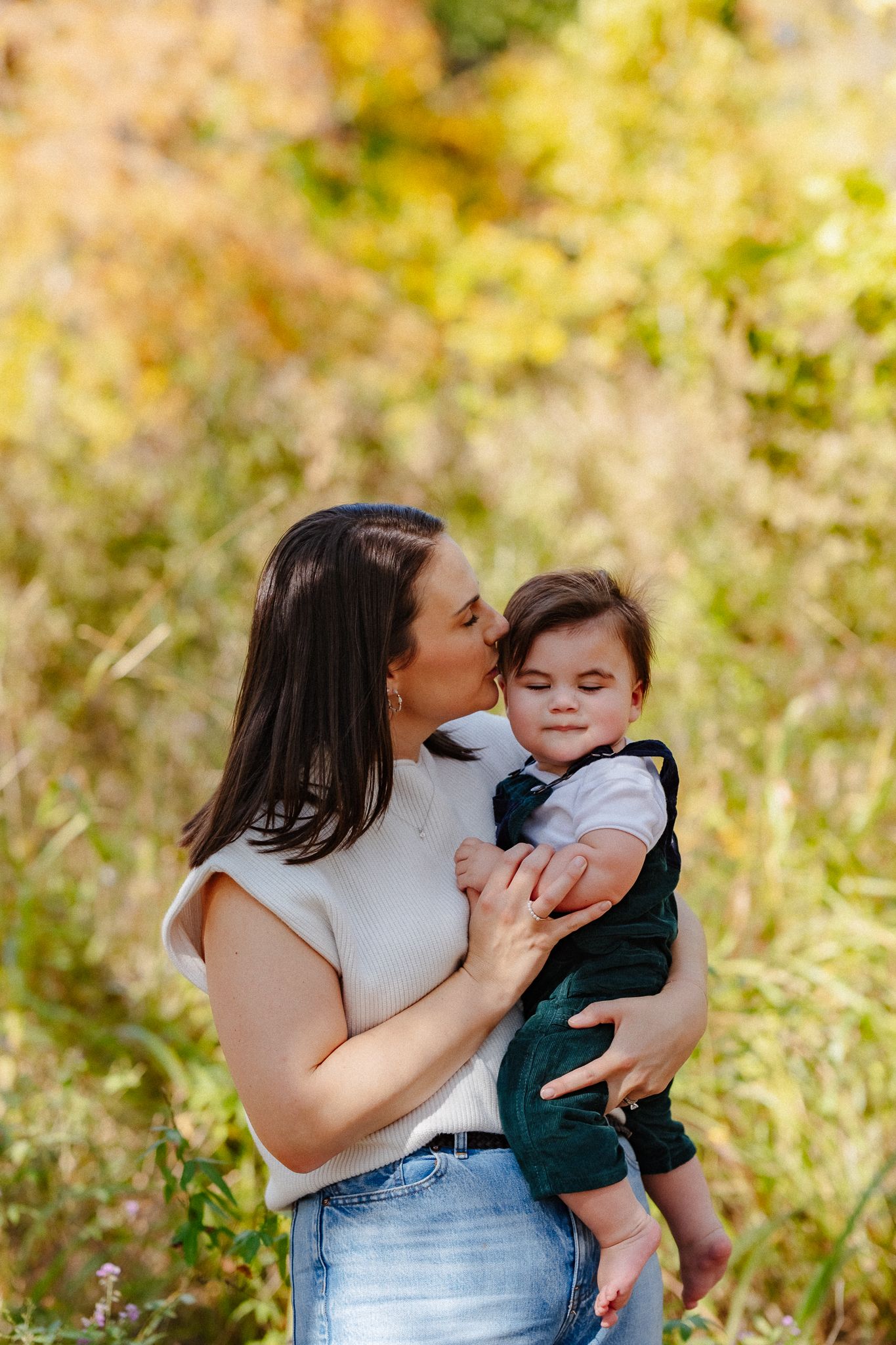 An intimate family portrait captured outdoors with soft autumn lighting and natural scenery.
