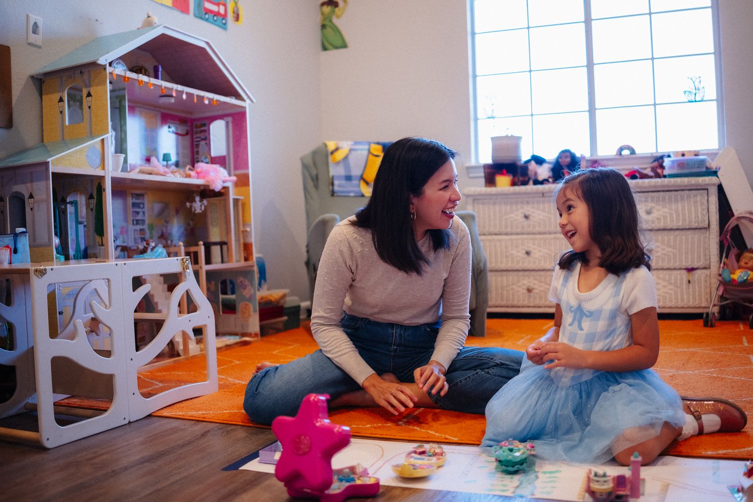 A playful moment in a child's room with toys and a dollhouse in the background.