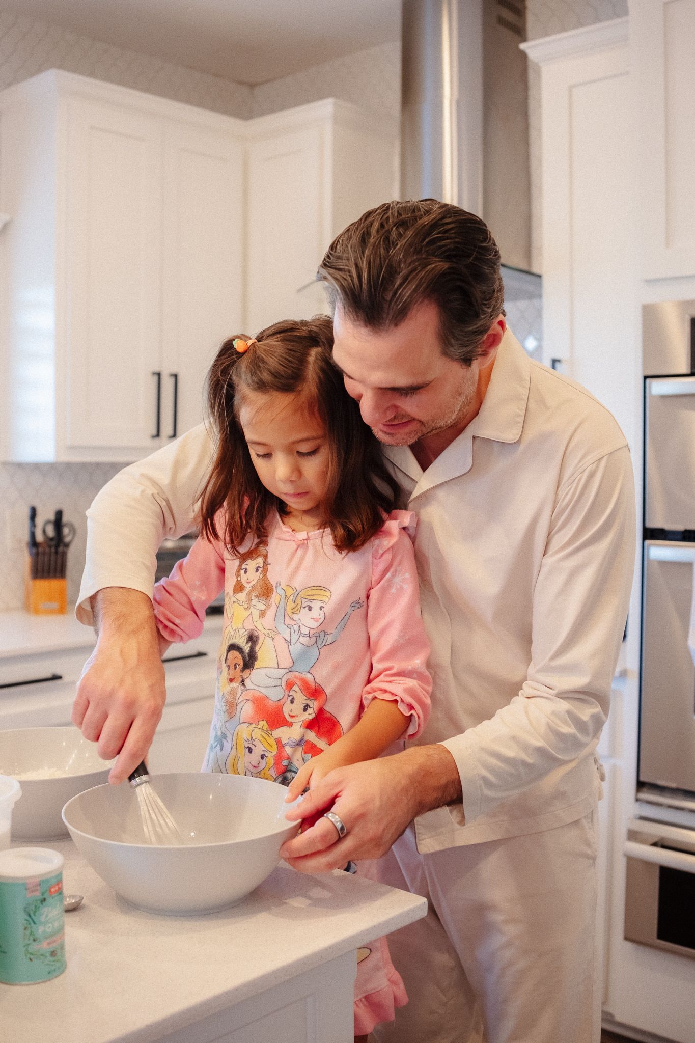 A cooking lesson in progress as two people work together mixing ingredients in a white bowl.