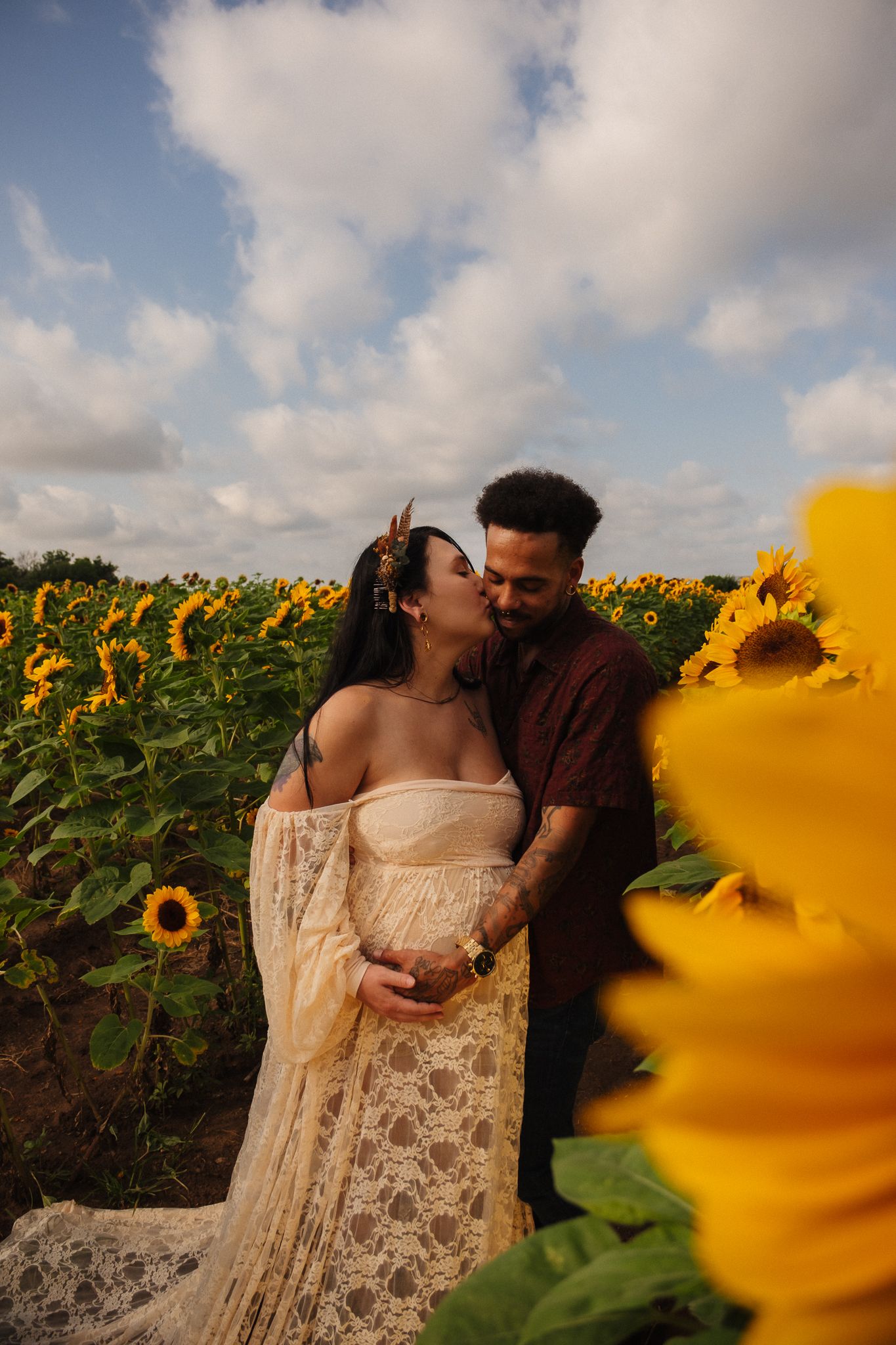 A romantic couple shares an intimate moment in a flowering sunflower field on a summer evening.