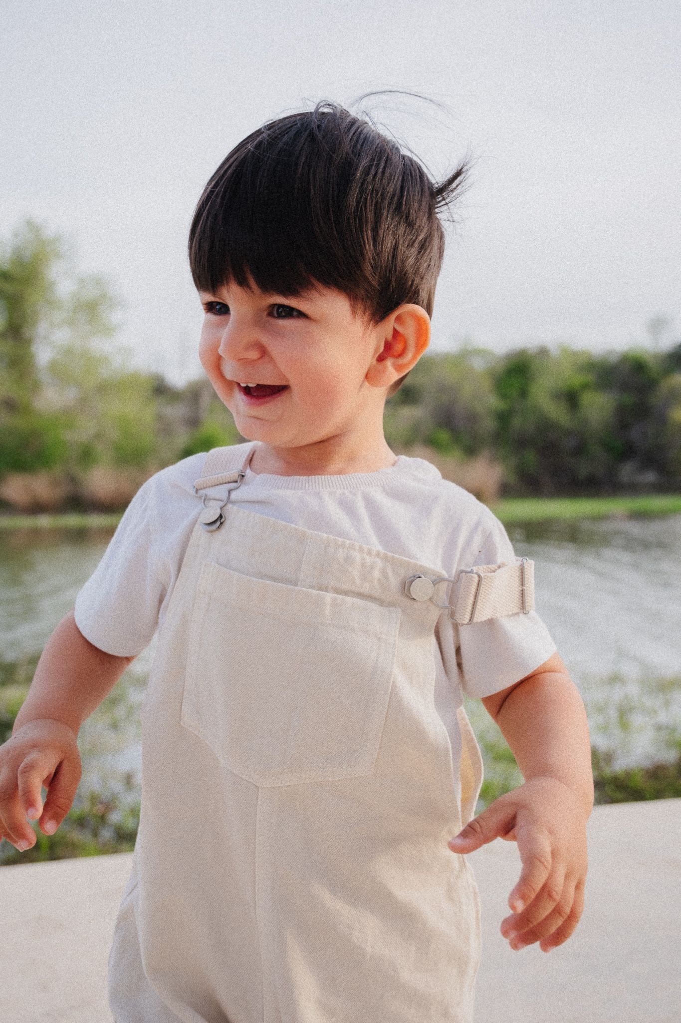 Series of cropped photos showing a child in white overalls playing by a lake on a sunny day.