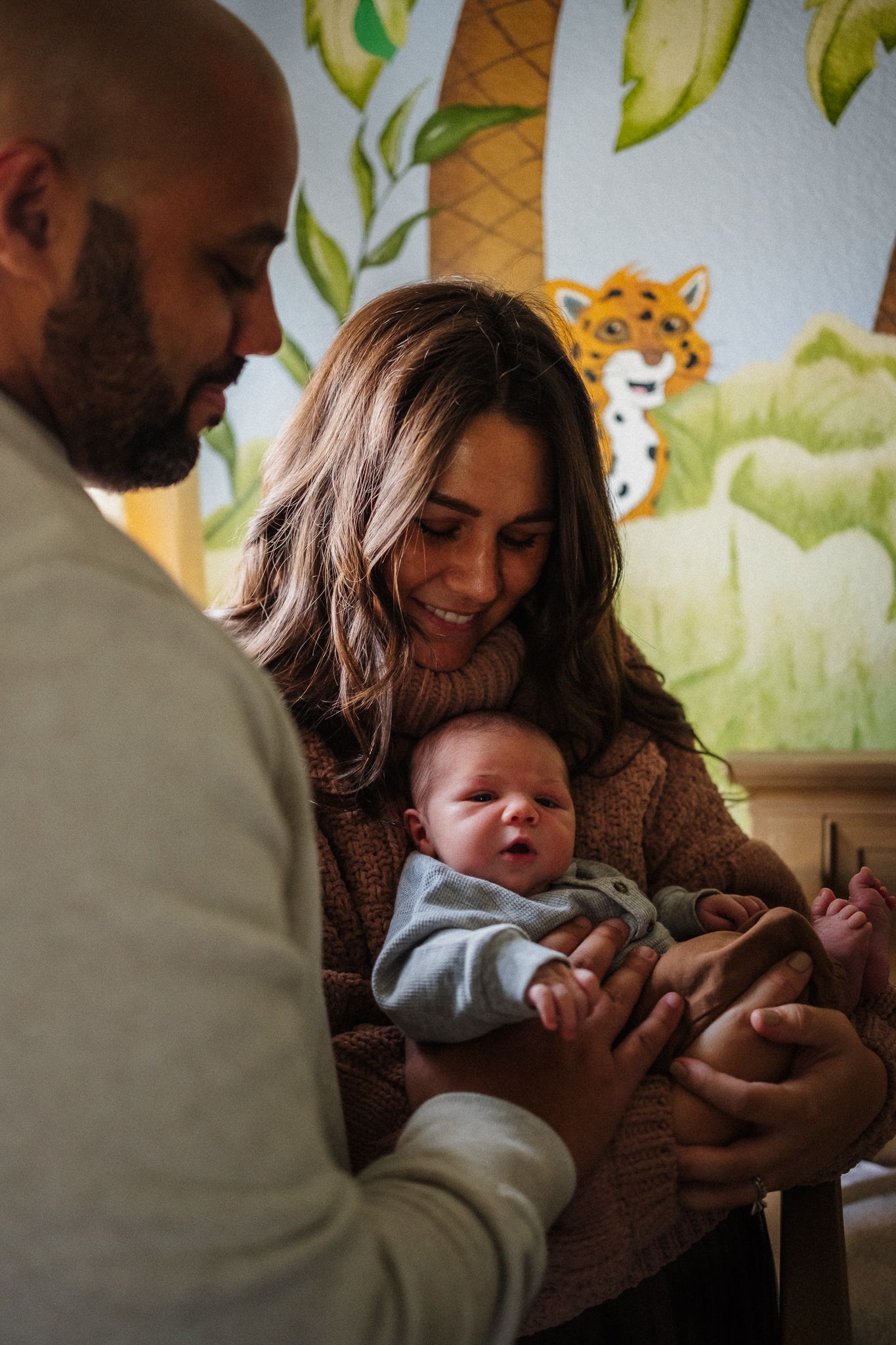 Family moment captured in nursery with painted woodland mural background.