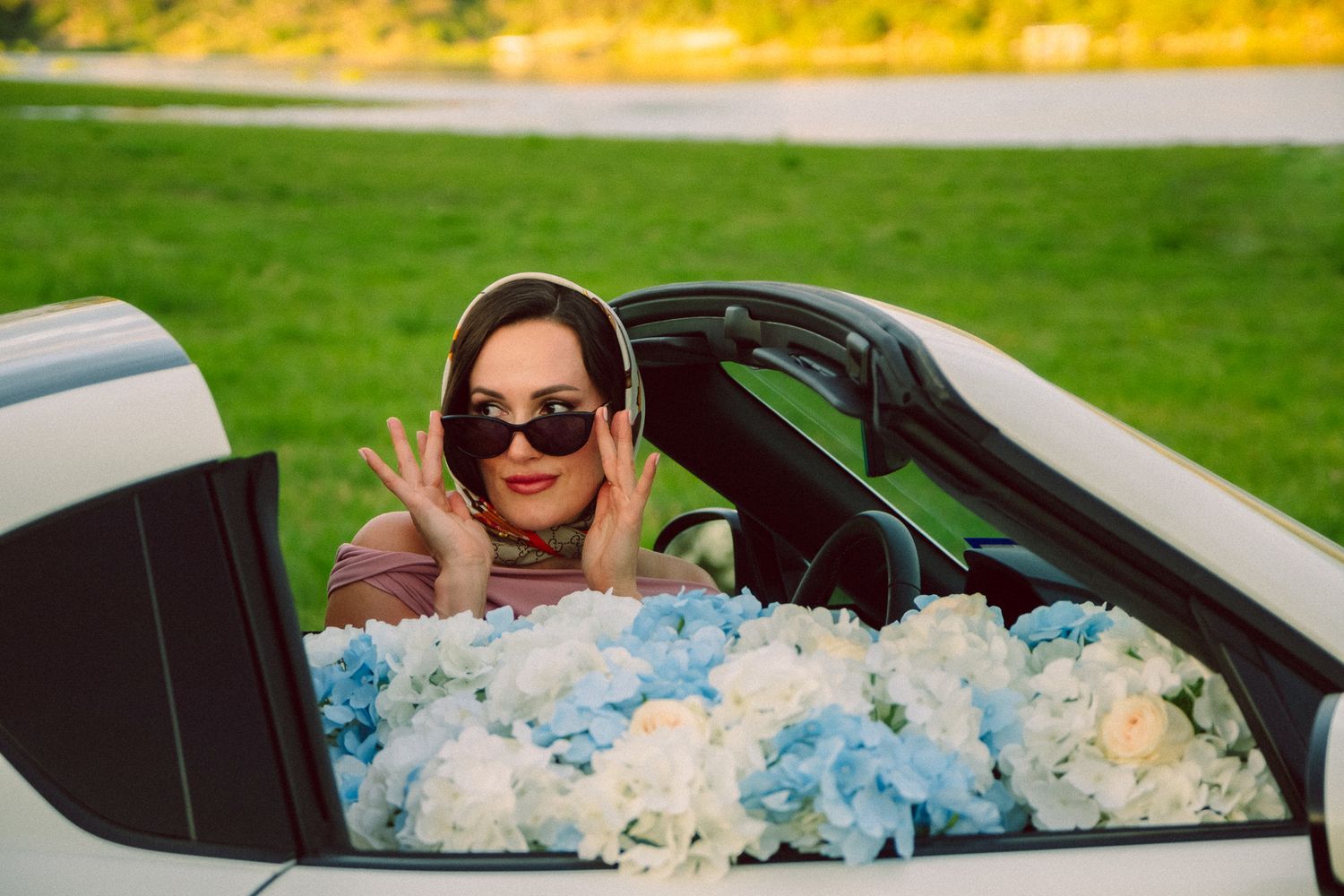 A person sits in a car surrounded by blue and white flowers decorating the interior.