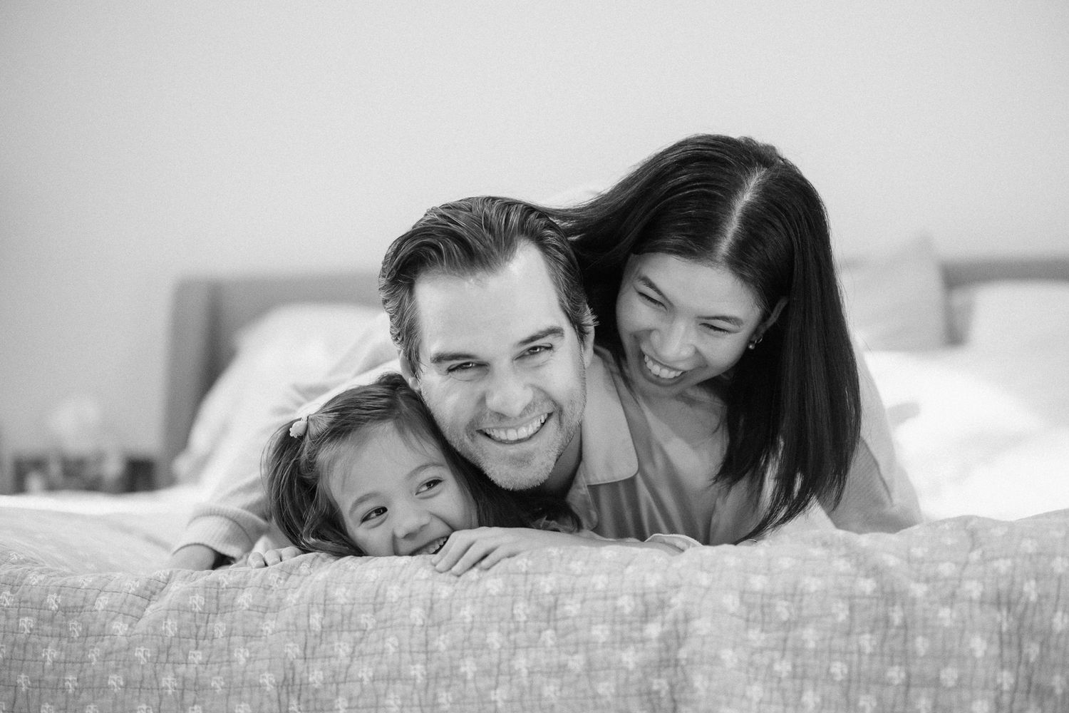 A series of black and white photos showing joyful family moments of parents and children cuddling together.