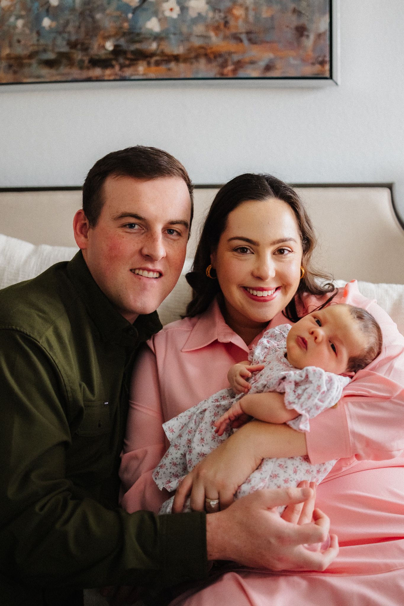 A series of intimate family photos showing parents bonding with their newborn baby in a cozy bedroom setting.