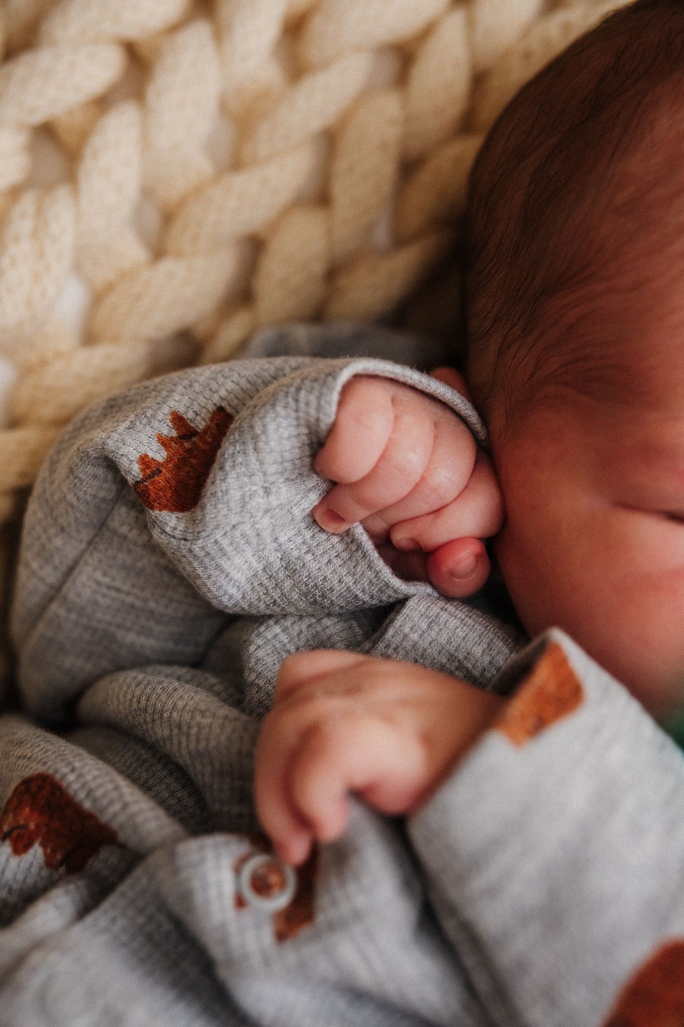 Close-up view of tiny baby feet in soft gray knit clothing.