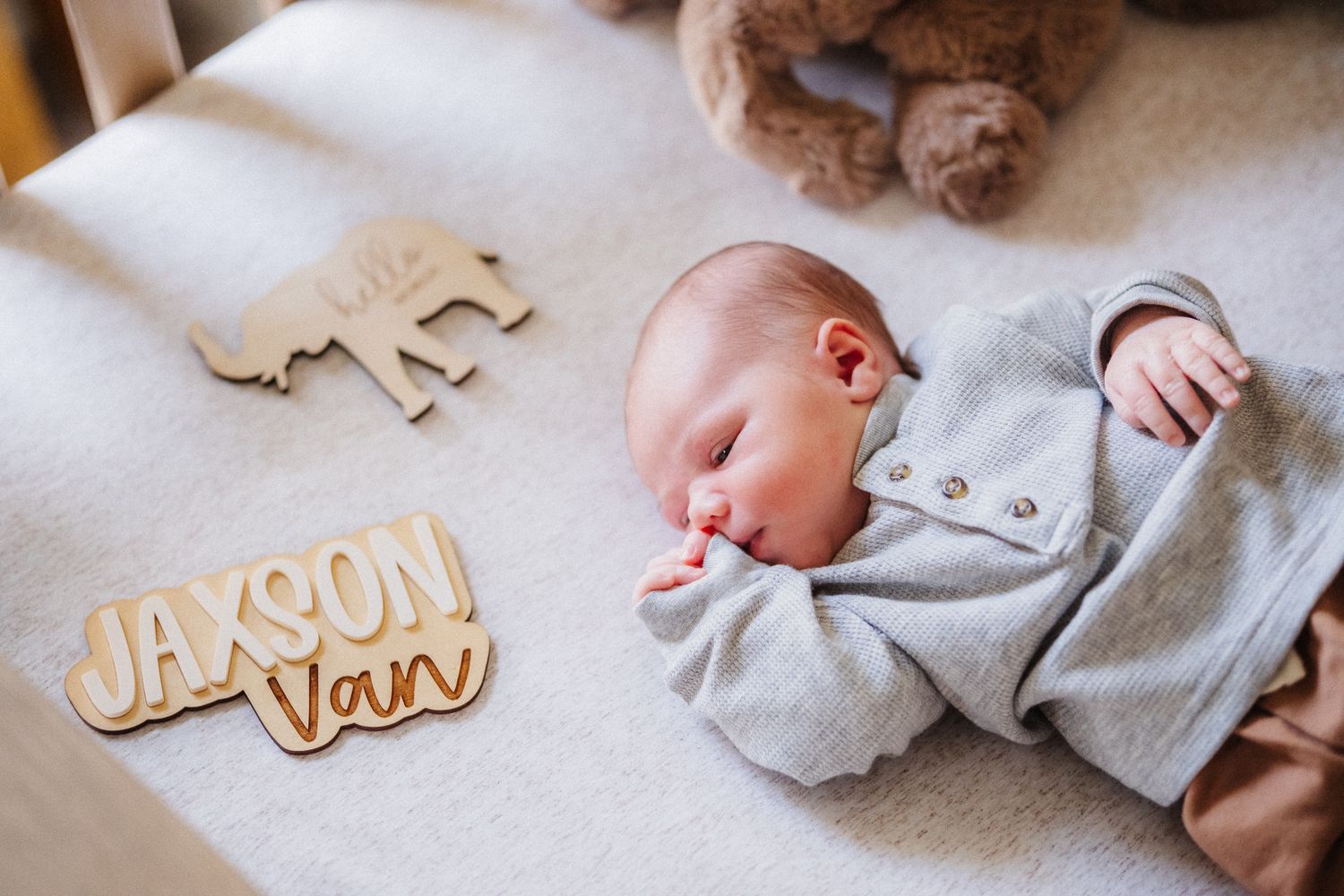 Newborn photography setup with wooden name letters and soft gray blanket.