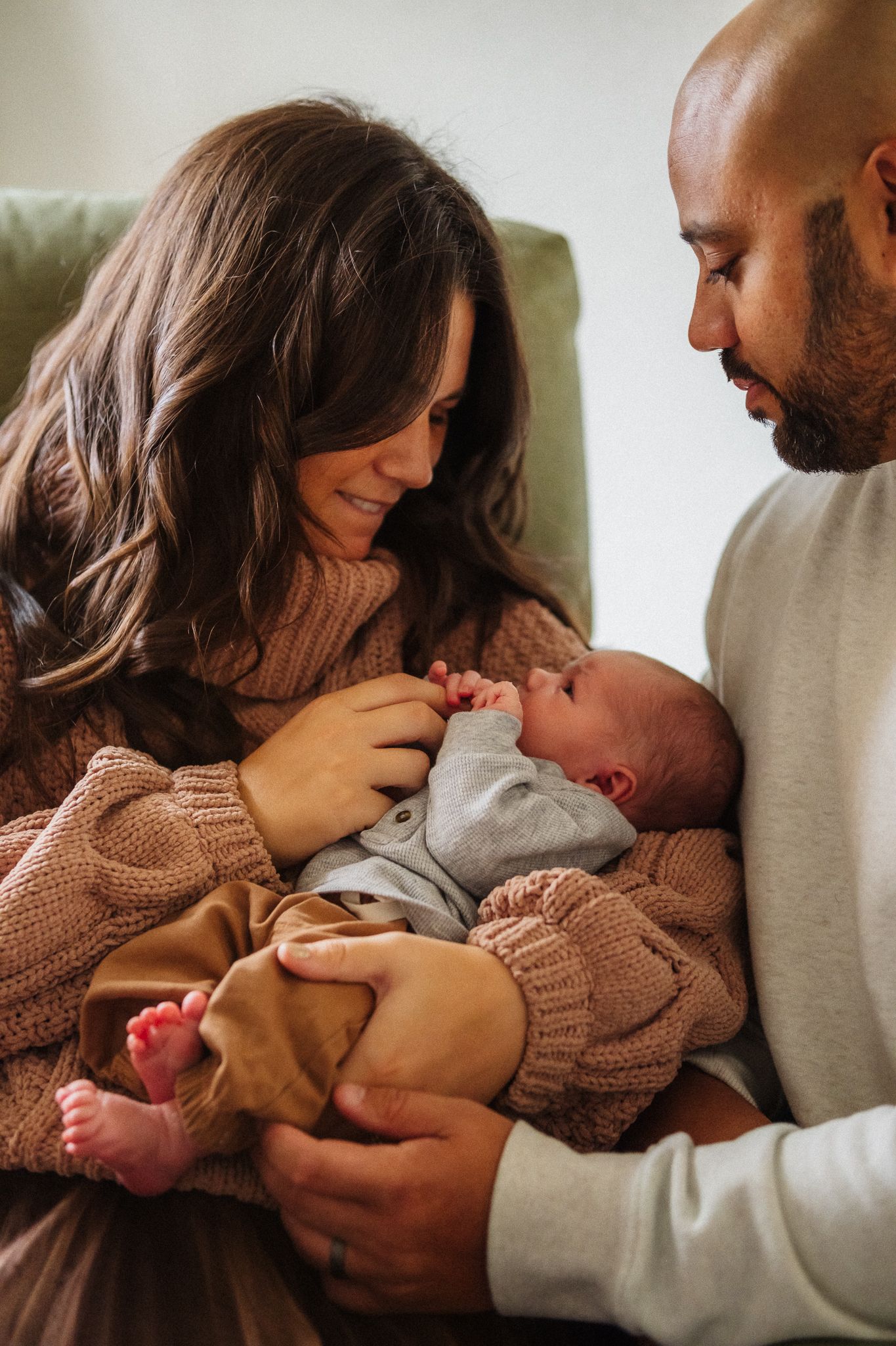 A tender family moment captured as parents cradle their newborn baby on a couch.