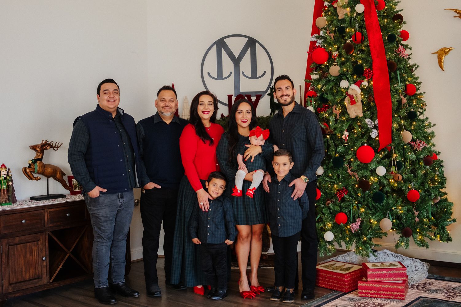A series of family holiday portraits showing multiple groups posing in front of decorated Christmas trees and festive decor.
