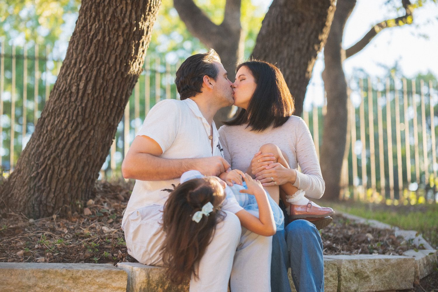 A sweet family photo series taken under a large tree with natural lighting and gentle embraces.