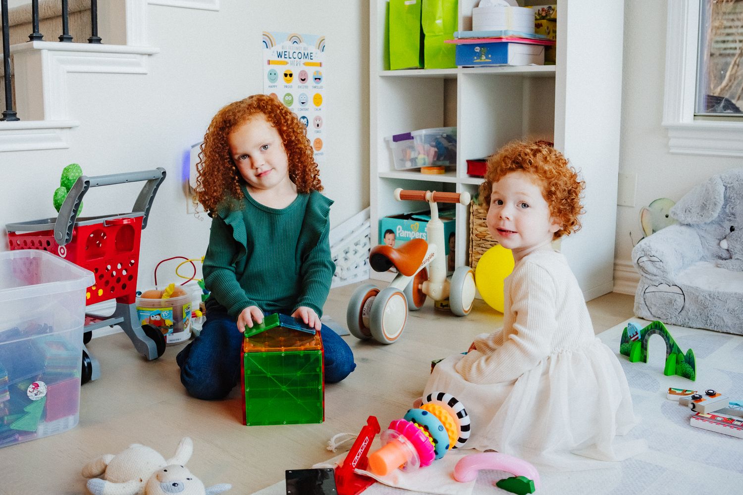 Children playing in a bright white playroom filled with colorful toys and storage solutions.