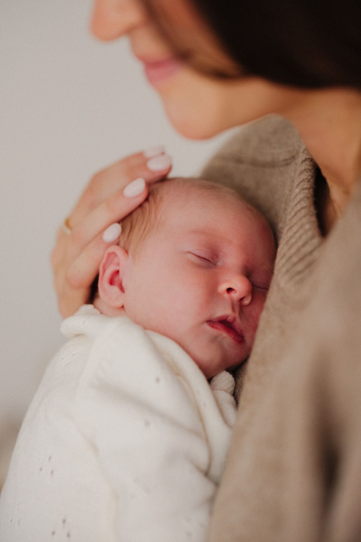 Close-up photos of a sleeping newborn baby wrapped in white blanket showing peaceful expressions.