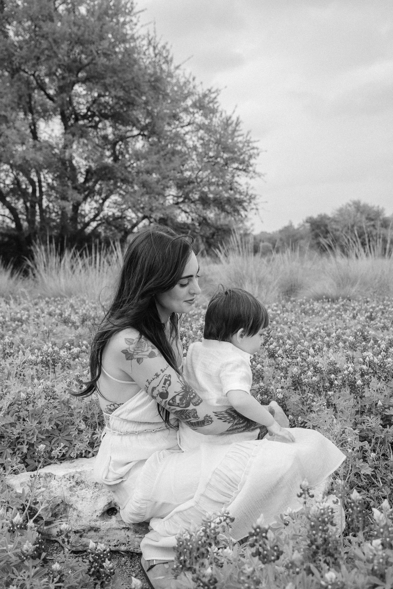 Black and white photo series of three people sitting together in a wildflower meadow on a sunny day.