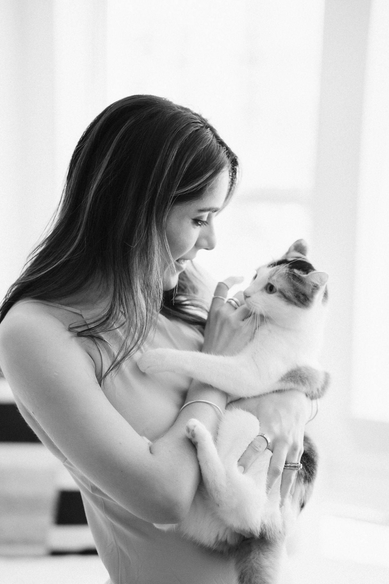 Black and white photo series showing tender moments between a person and a small white kitten in natural window light.