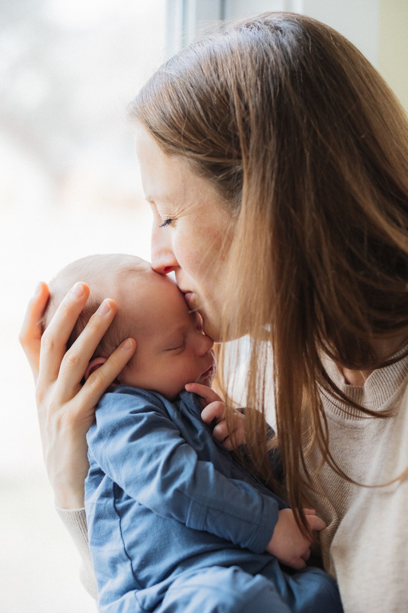 A tender moment between parent and baby wearing blue as they share an intimate embrace.