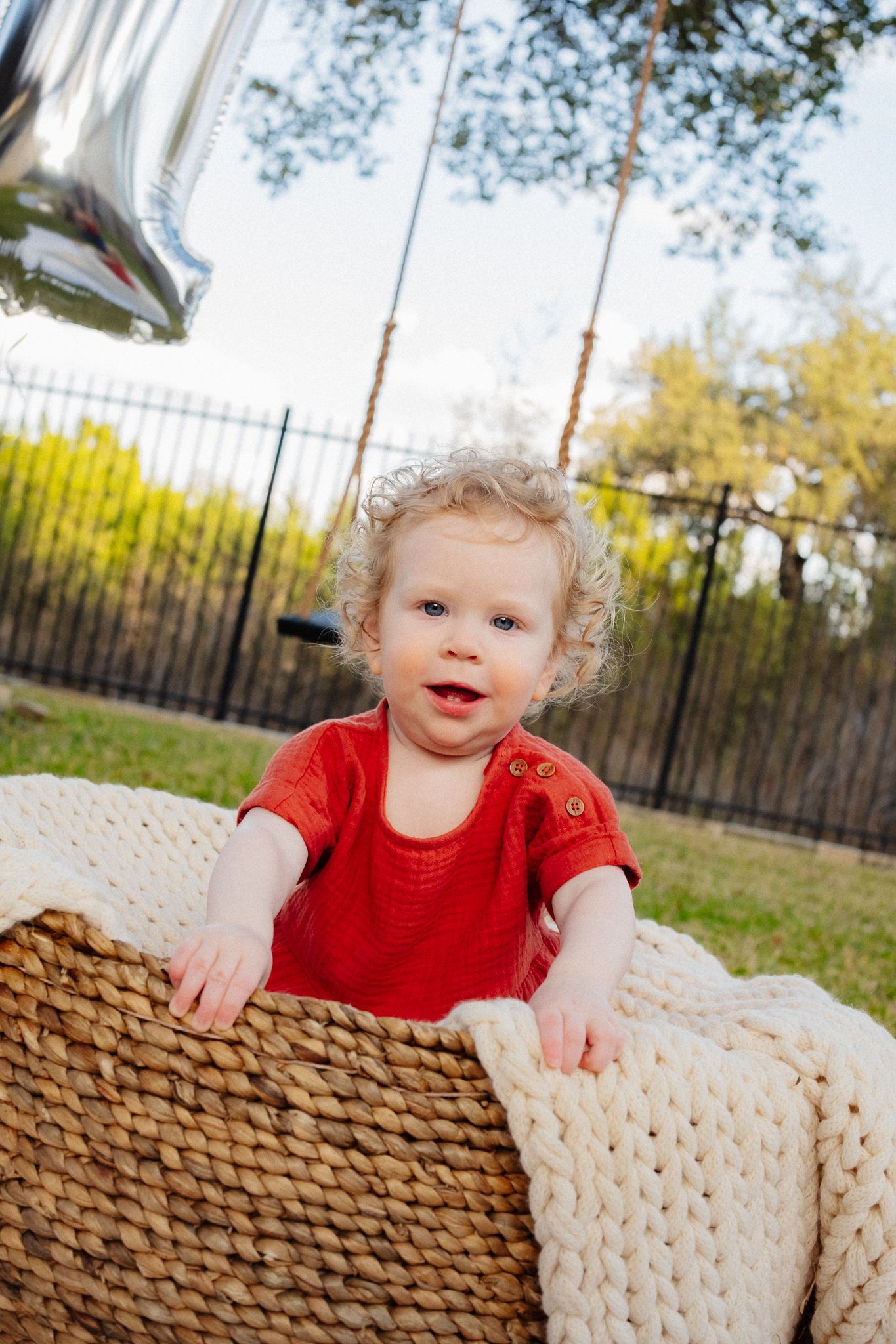 A series of photos showing a toddler in a red shirt playing with a cream-colored knit pillow outdoors.