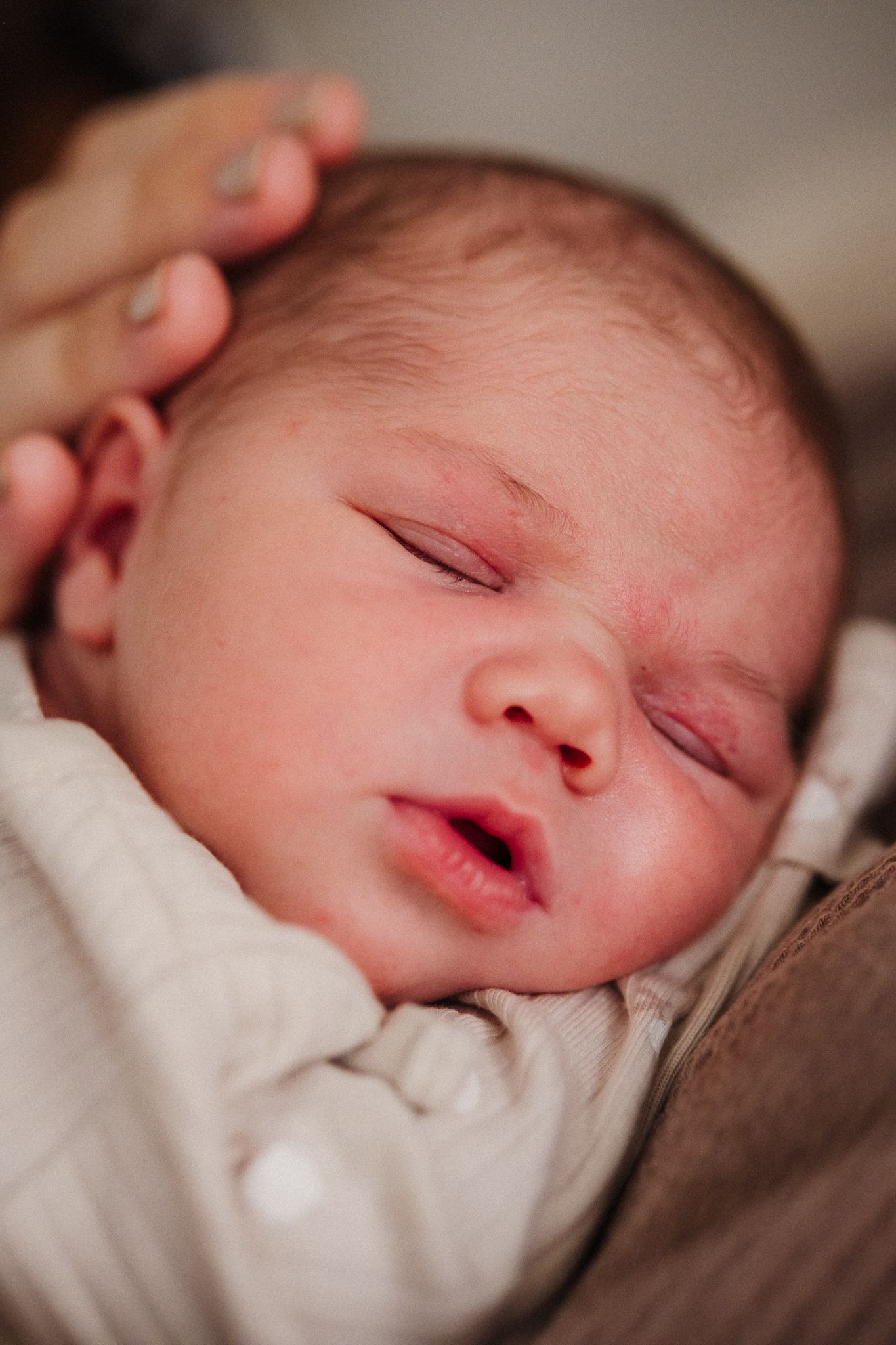 A sleeping newborn baby in soft white blankets shown from different angles in a series of closeup shots.