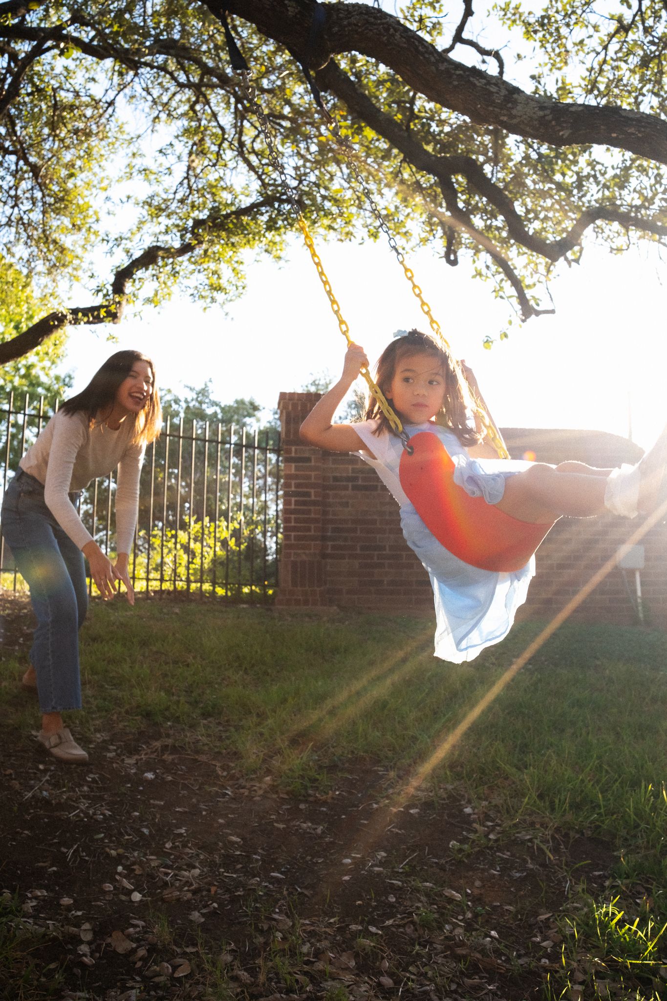 Sequence of playful swinging motion shots at sunset with a tree and brick wall in the background.