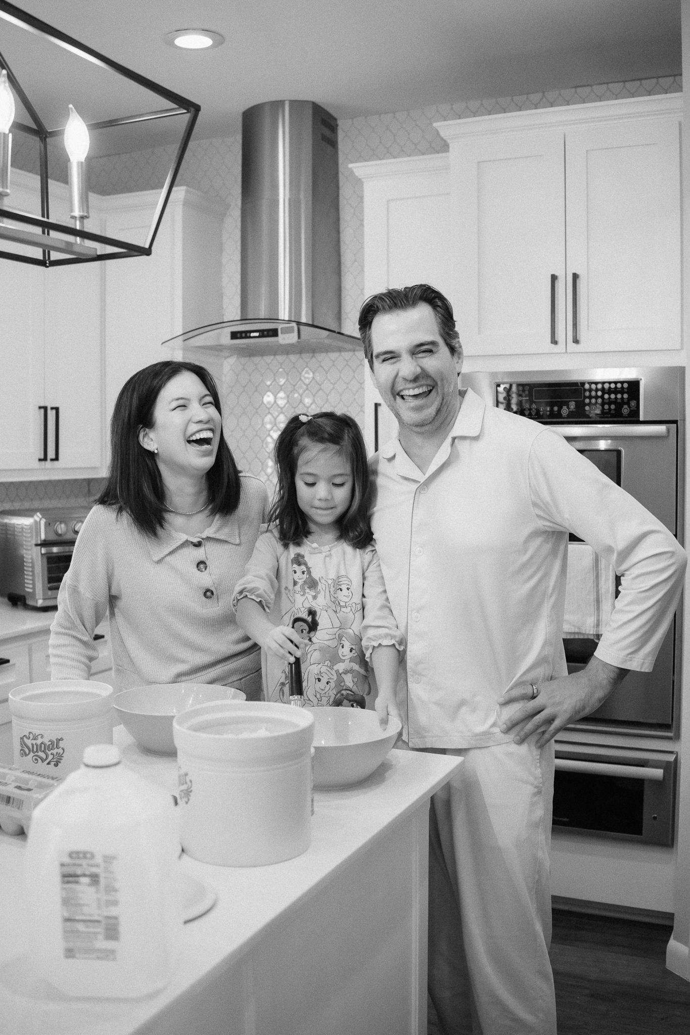 Black and white photo of a family enjoying time together while baking in their kitchen.