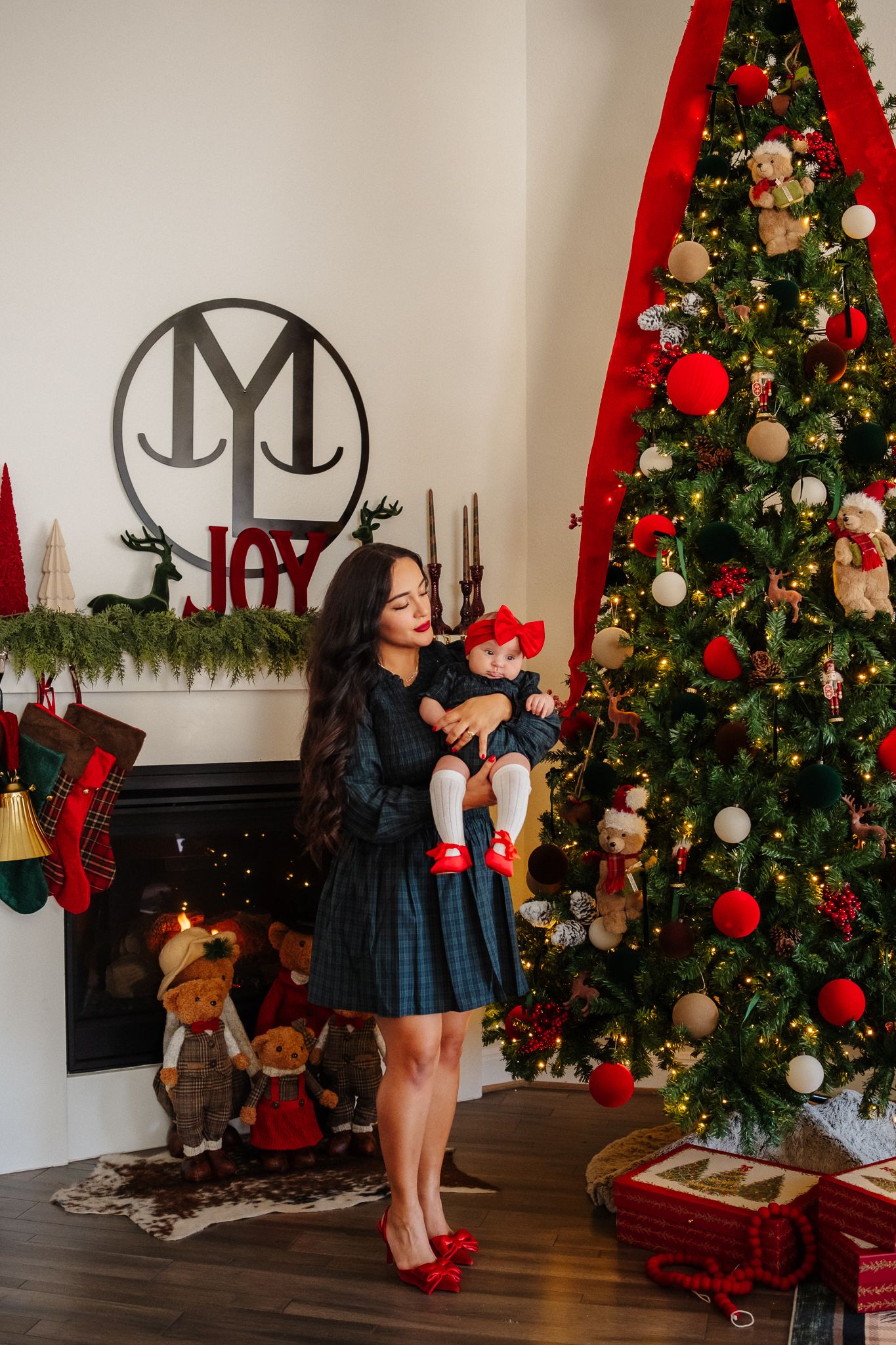 Decorated Christmas trees with red and white ornaments line a wall with holiday decor and stockings.