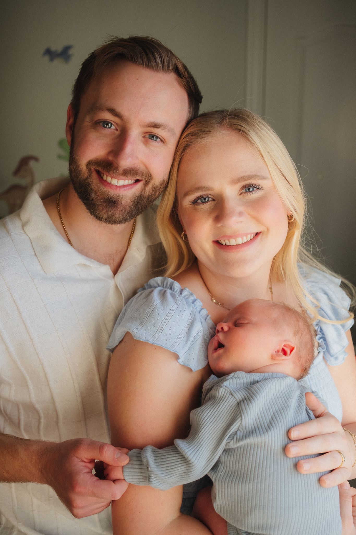 A couple in white and light blue clothing share tender moments with their baby in a series of intimate family portraits.