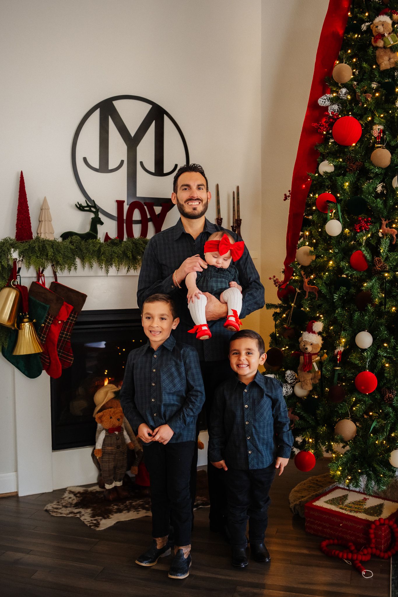 A cozy Christmas scene with matching denim outfits against a decorated tree and festive decor.
