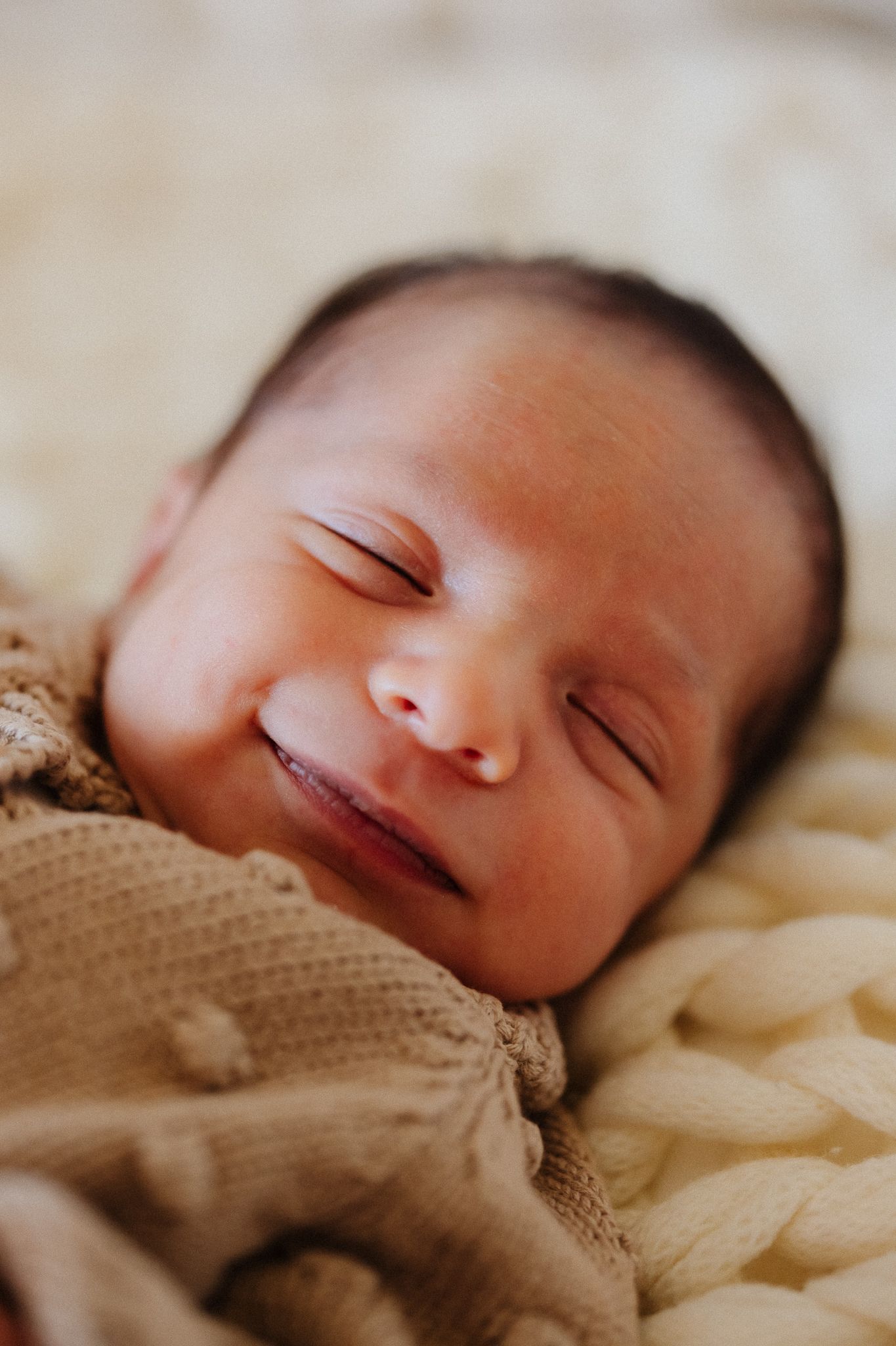 A sleeping newborn baby wrapped in a brown knit blanket shown in a series of close-up portraits.