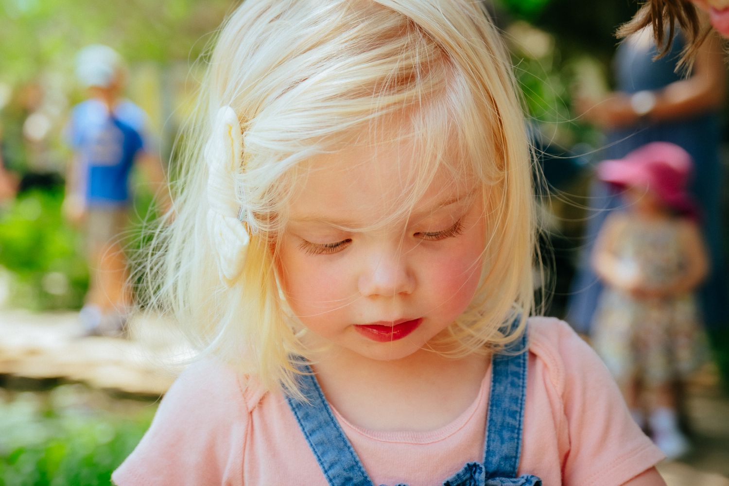 A child in a pink shirt plays outside on a sunny summer day while enjoying outdoor activities.