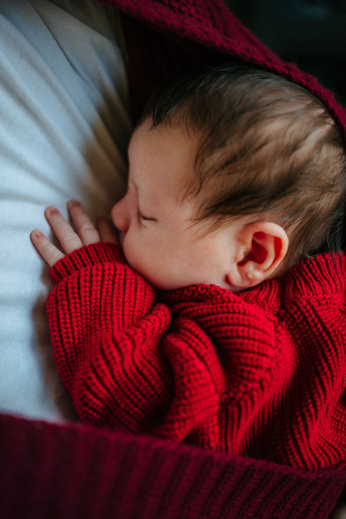 Sleeping baby wearing red knit sweater captured in series of peaceful close-up shots.