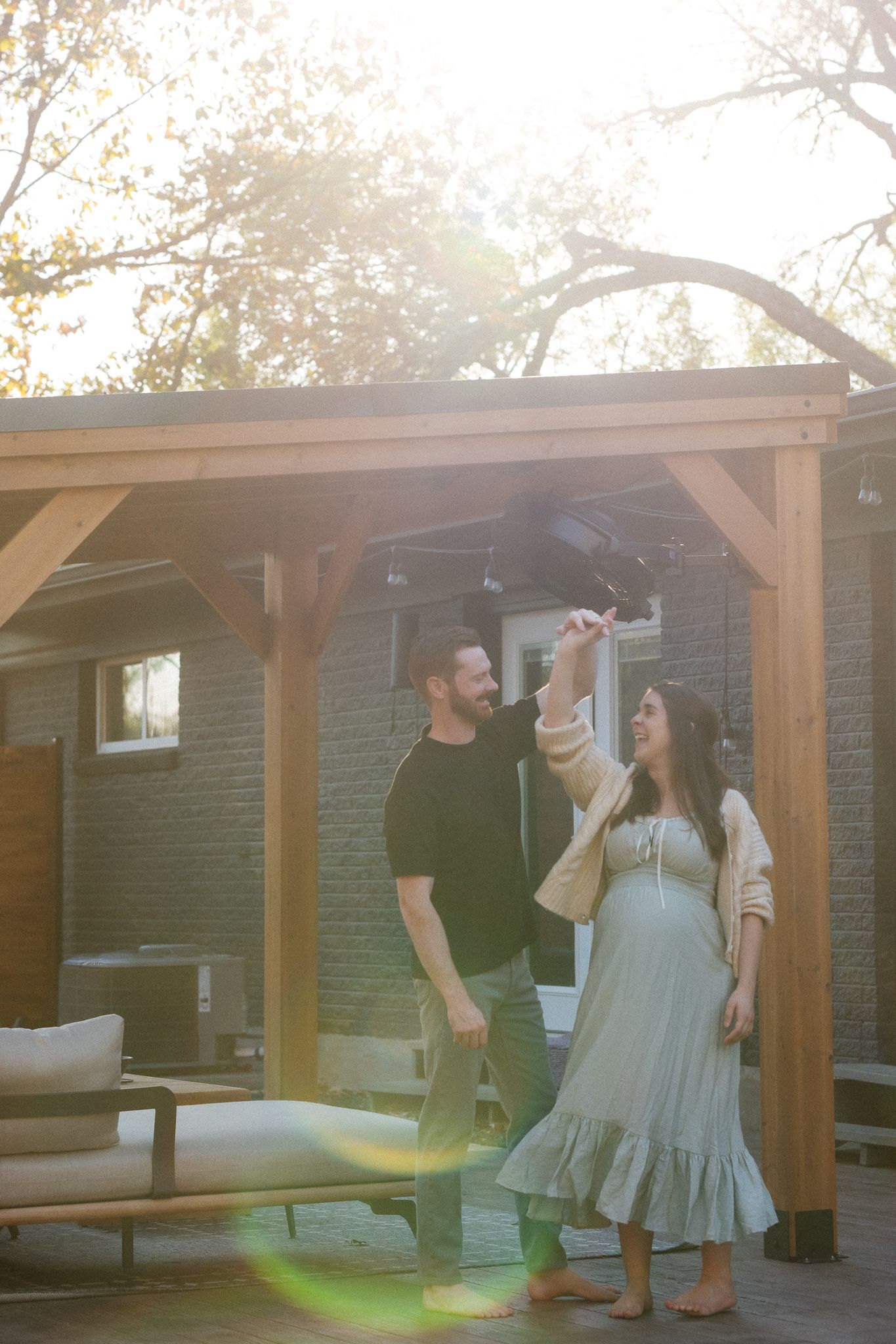 Family gathering under a wooden pergola during golden hour with sun flares.