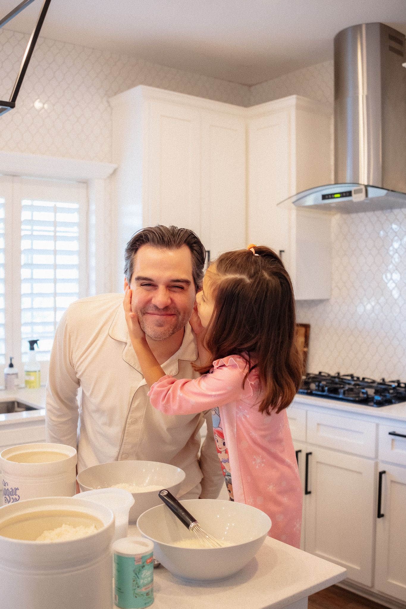 A series of photos showing a parent and child baking together in a bright white modern kitchen.