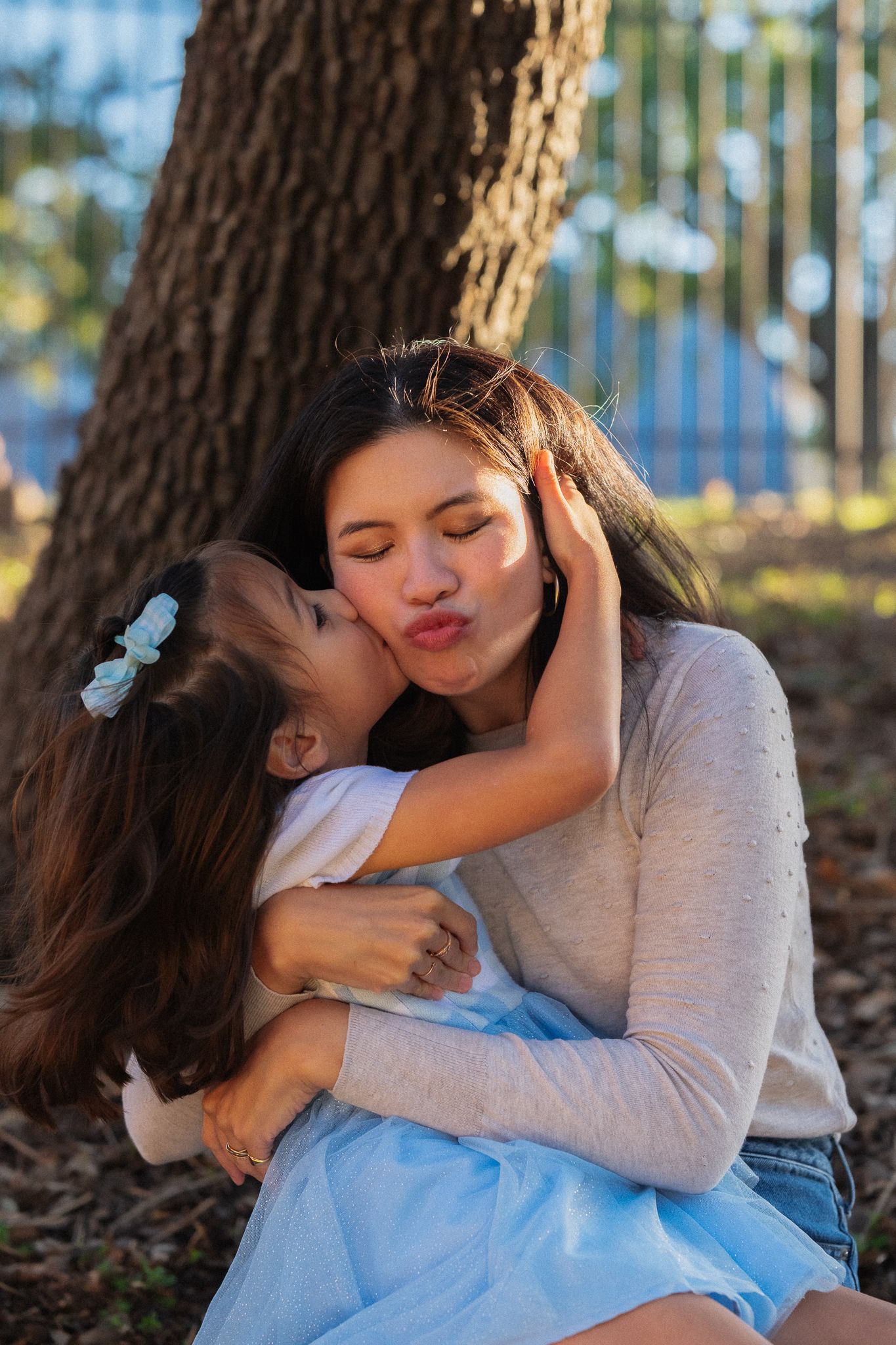 Tender family moment captured in a series of four intimate embraces under tree branches in natural lighting.