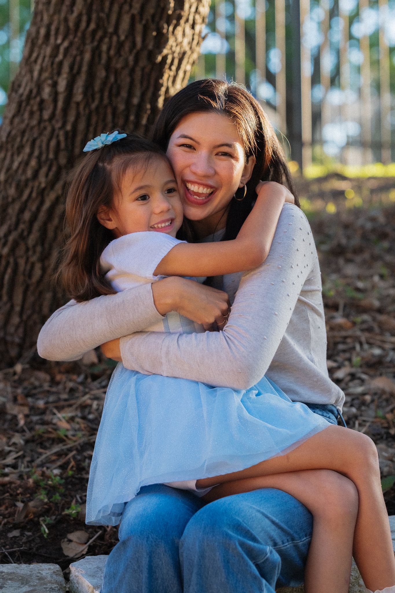 A heartwarming series of embraces between two people sitting under a tree with dappled sunlight filtering through.