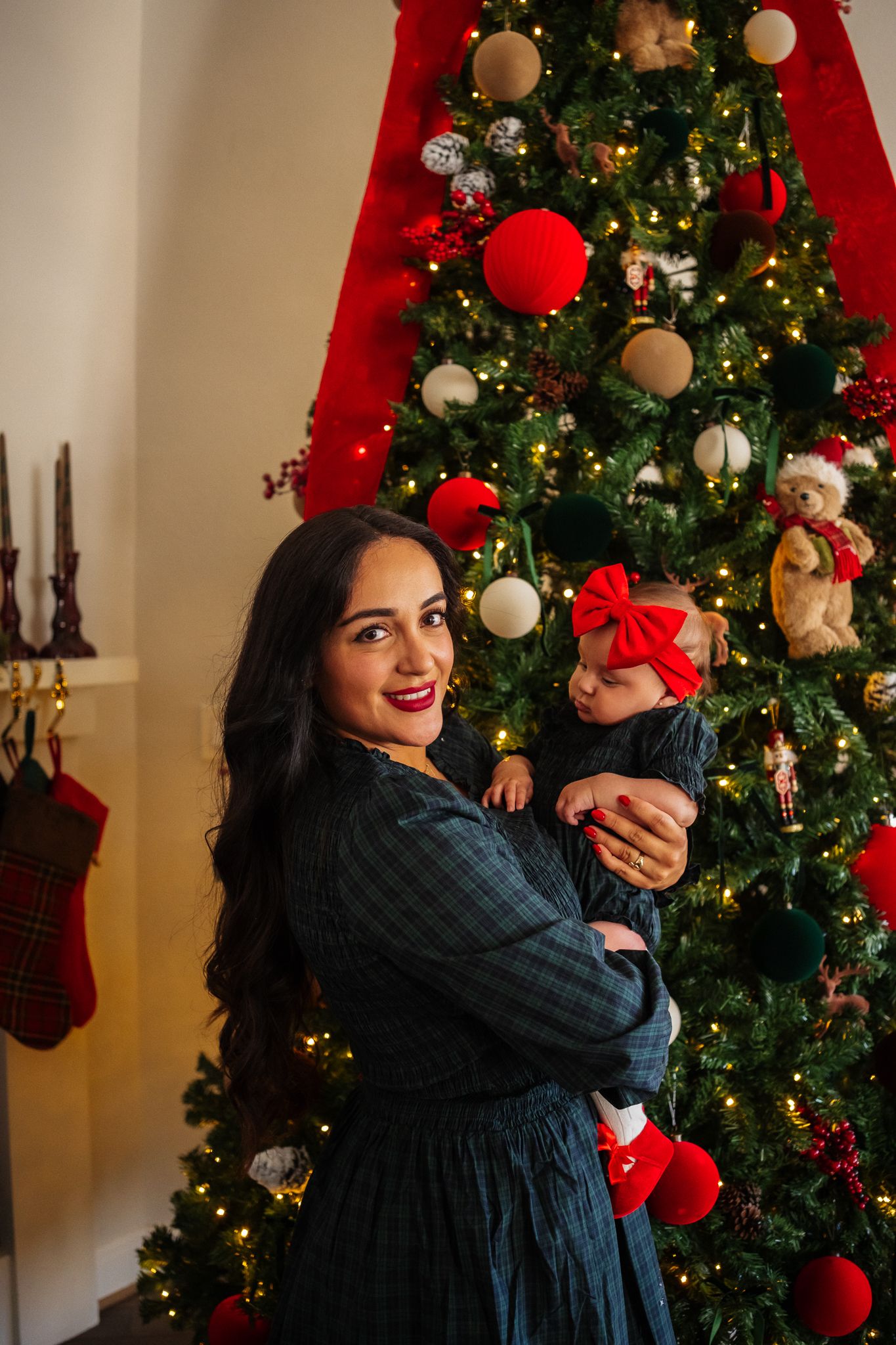 A festive holiday scene with a decorated Christmas tree and red stockings hanging in the background.