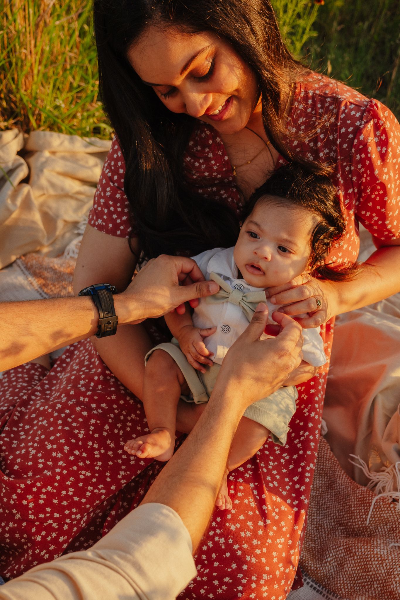A tender family moment captured during golden hour as they spend time together on a picnic blanket outdoors.