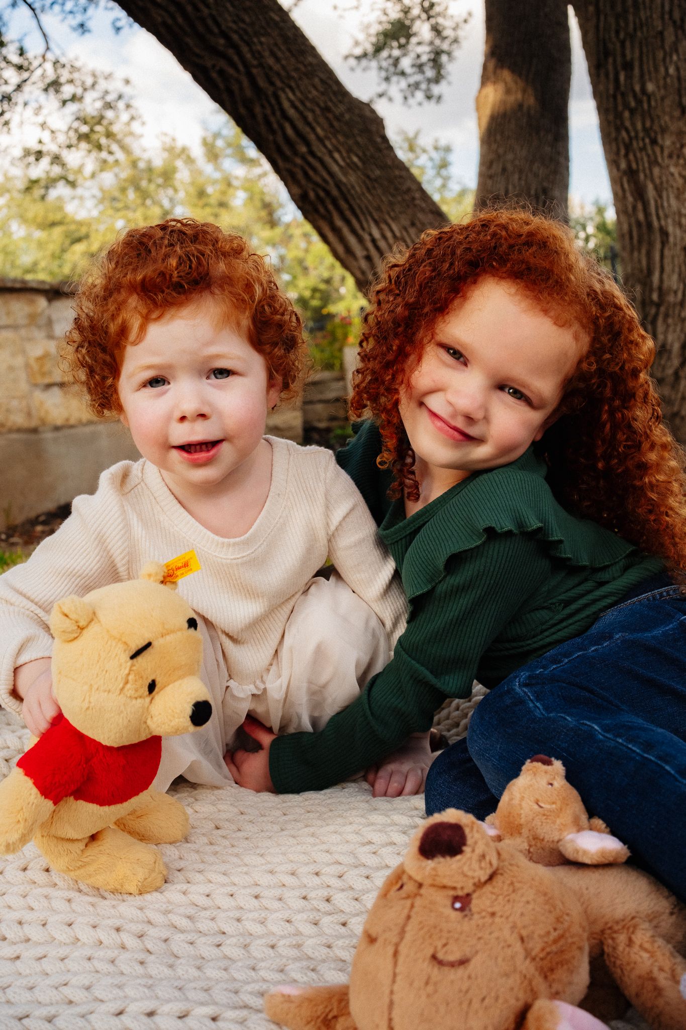 Sweet moments captured of children playing with plush toys during an outdoor photo session.