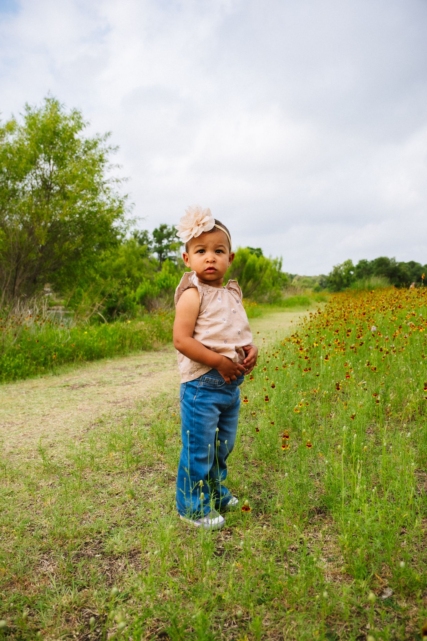 Small child exploring a wildflower meadow on a cloudy summer day.