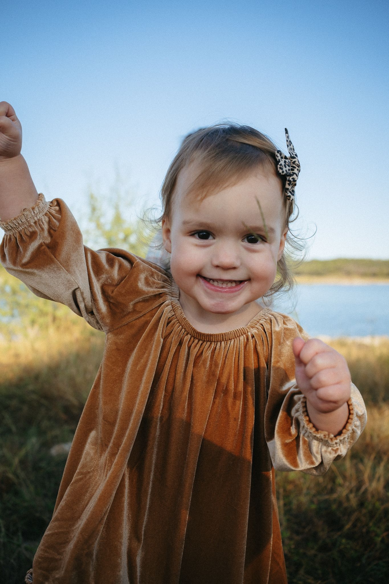 A child wearing a brown velvet dress plays outdoors in a series of candid moments at sunset.