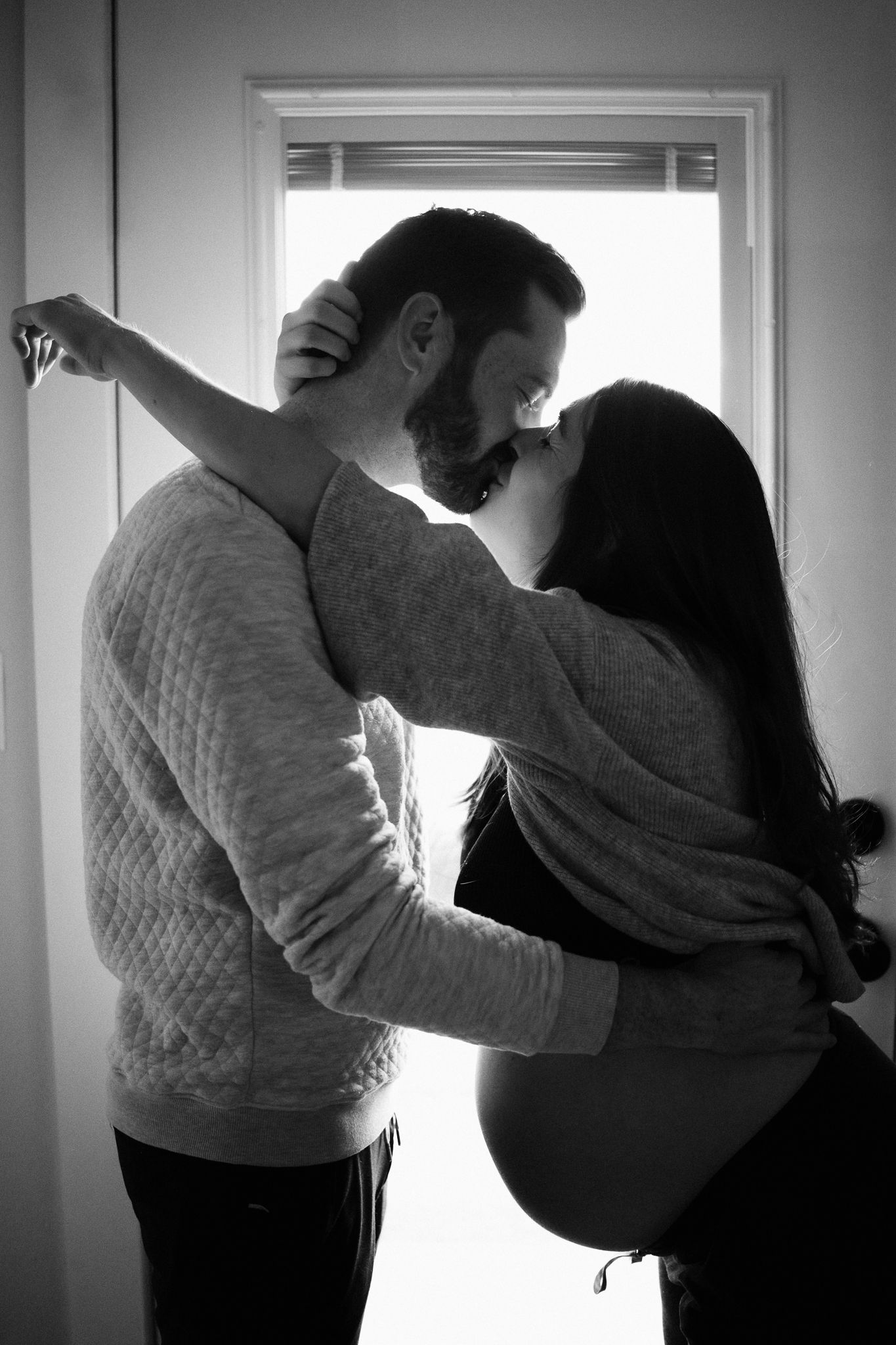 Black and white photo series showing silhouettes of two people embracing in front of bright windows.