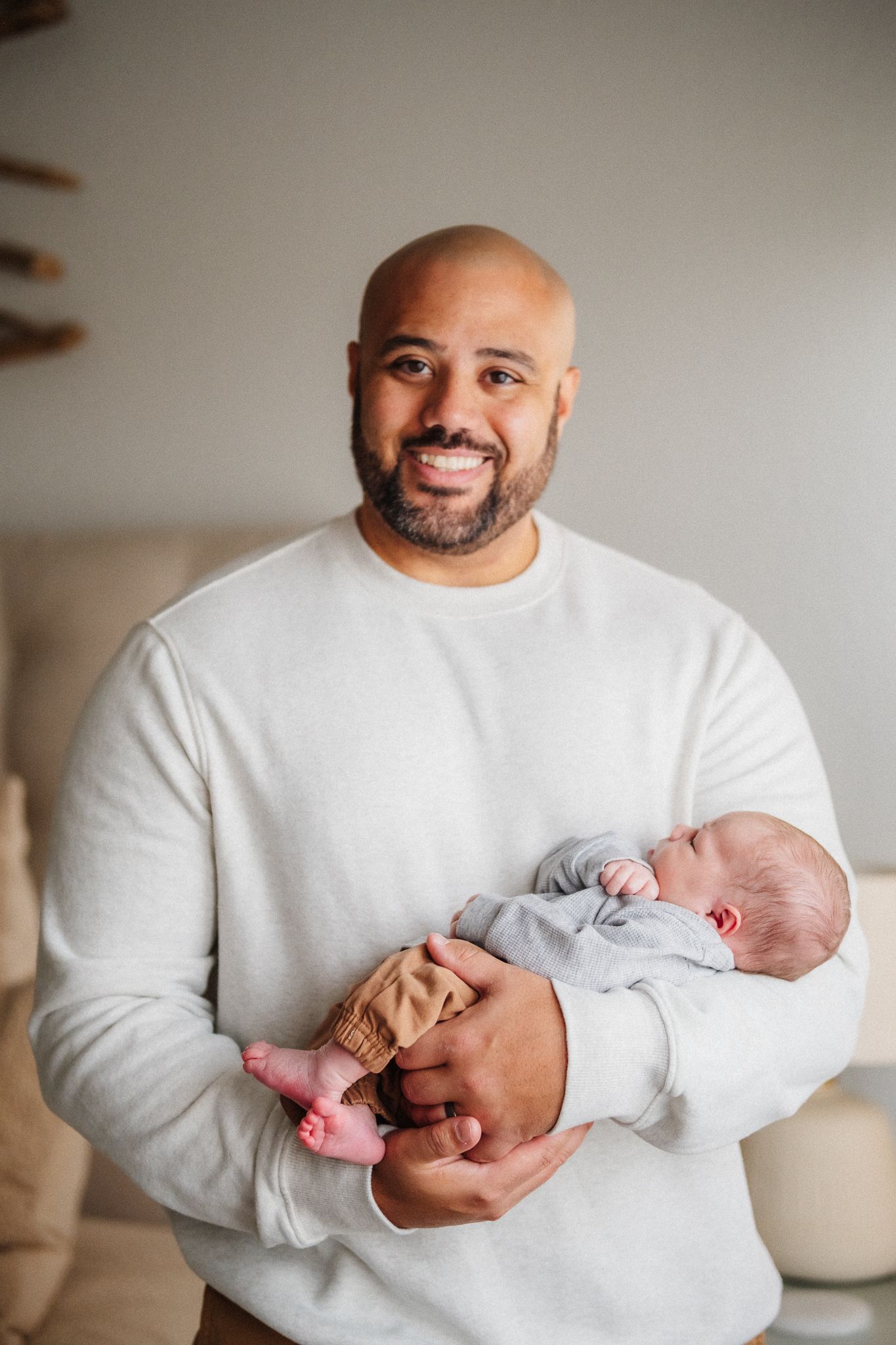 Parent in white sweater cradling sleeping newborn baby.