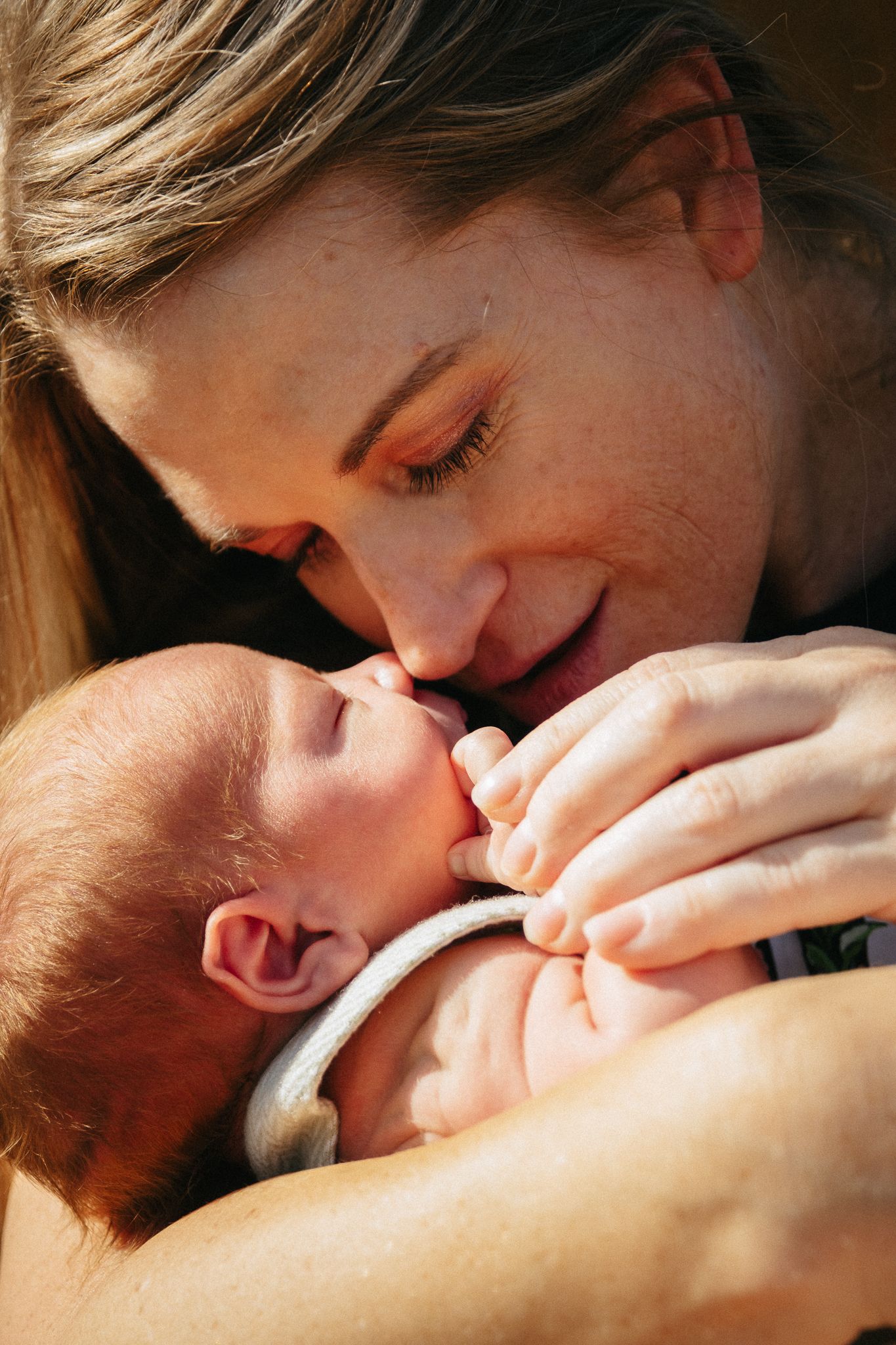 A tender moment between parent and newborn baby captured in warm natural light.