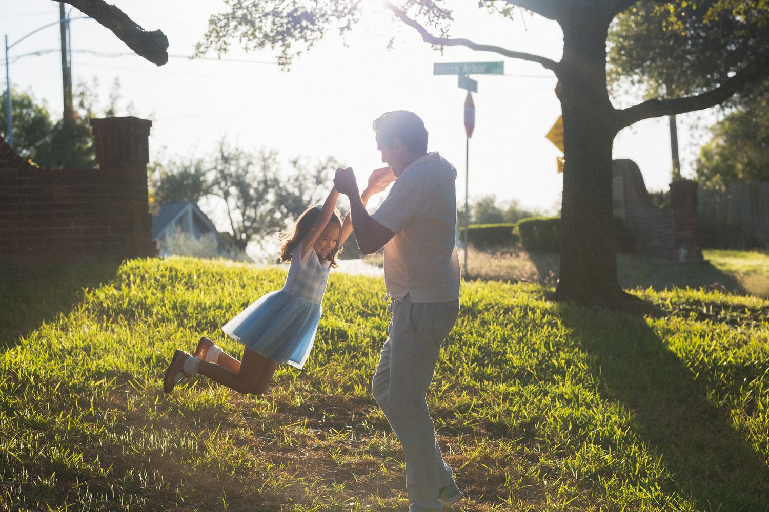 Family playing and running together on a grassy hill during sunset.