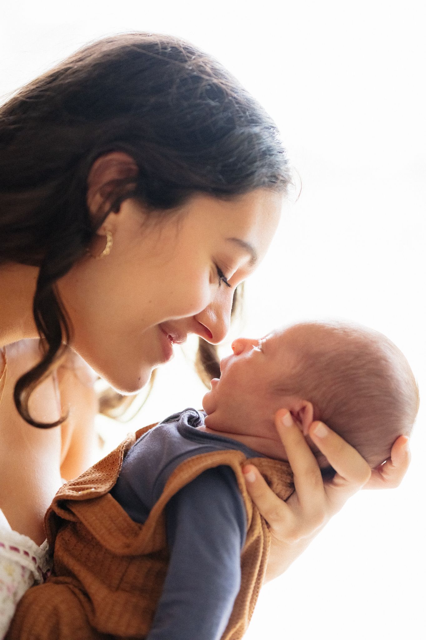 A tender moment captured in warm sunlight as a parent holds their newborn baby close.