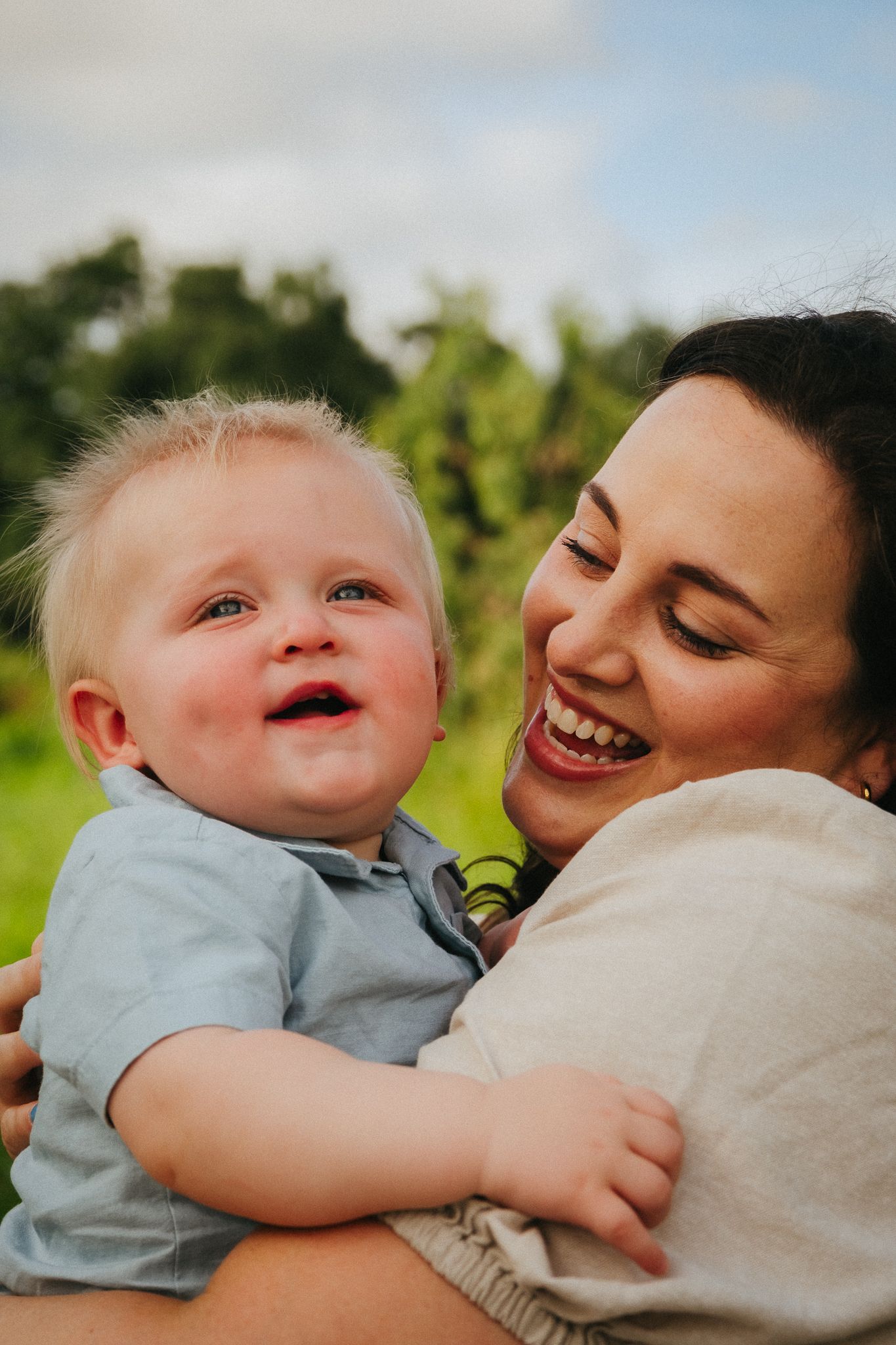 A heartwarming sequence of candid moments between a parent and baby playing outdoors in natural lighting.
