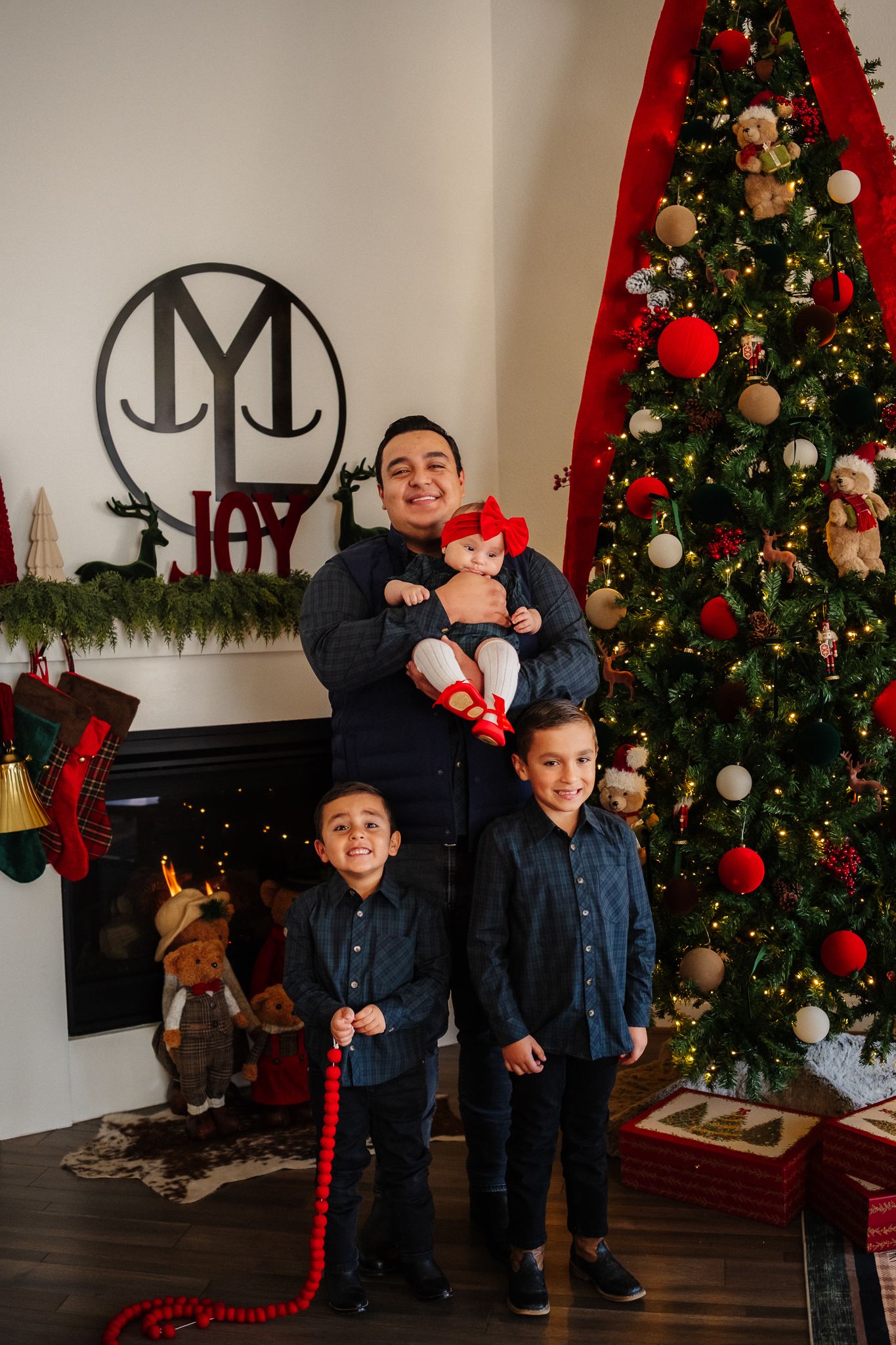 A sequence of playful holiday photos with matching denim outfits in front of a decorated Christmas tree with red ornaments.