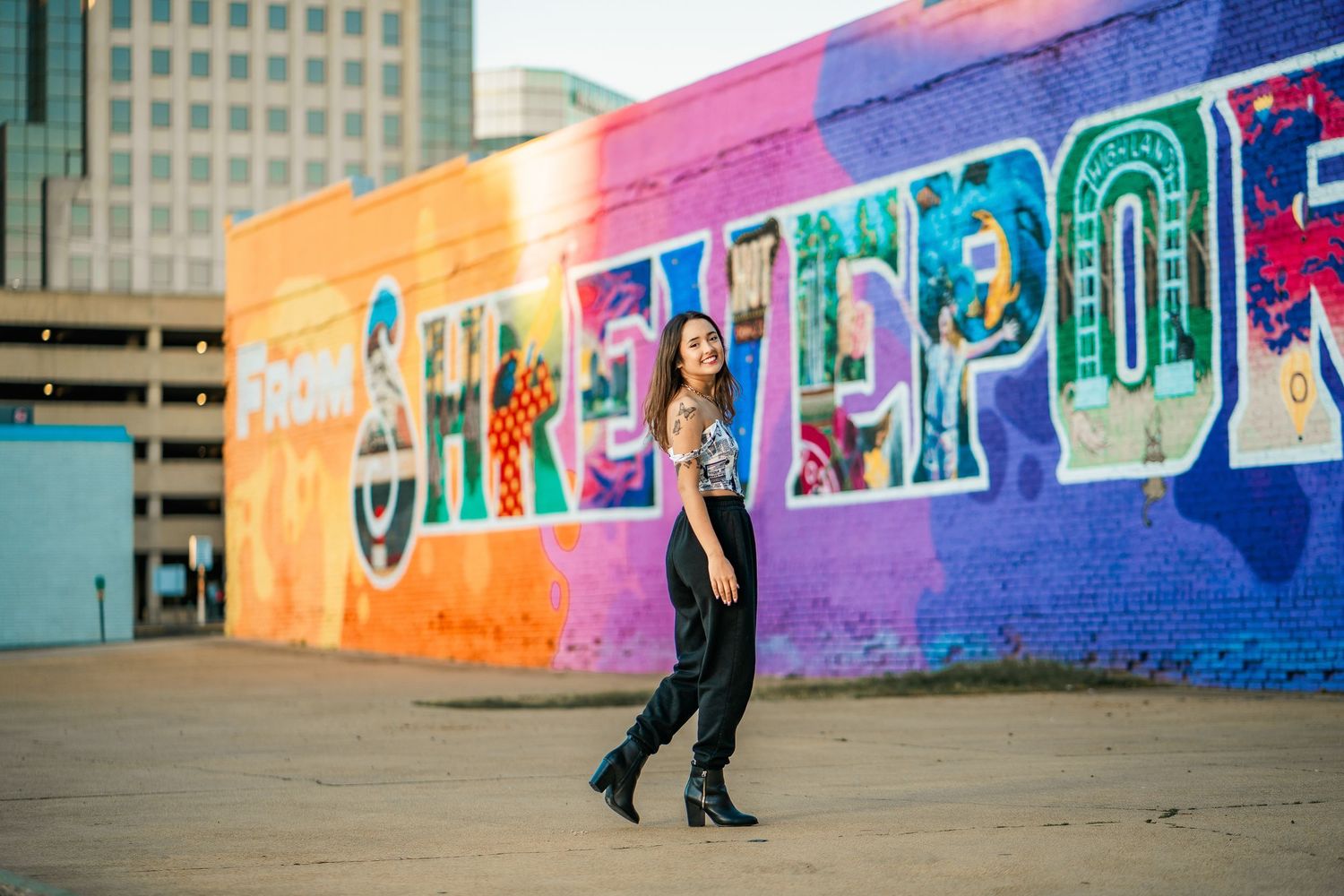 A colorful mural serves as backdrop to people dancing in an outdoor urban space against bright painted walls.