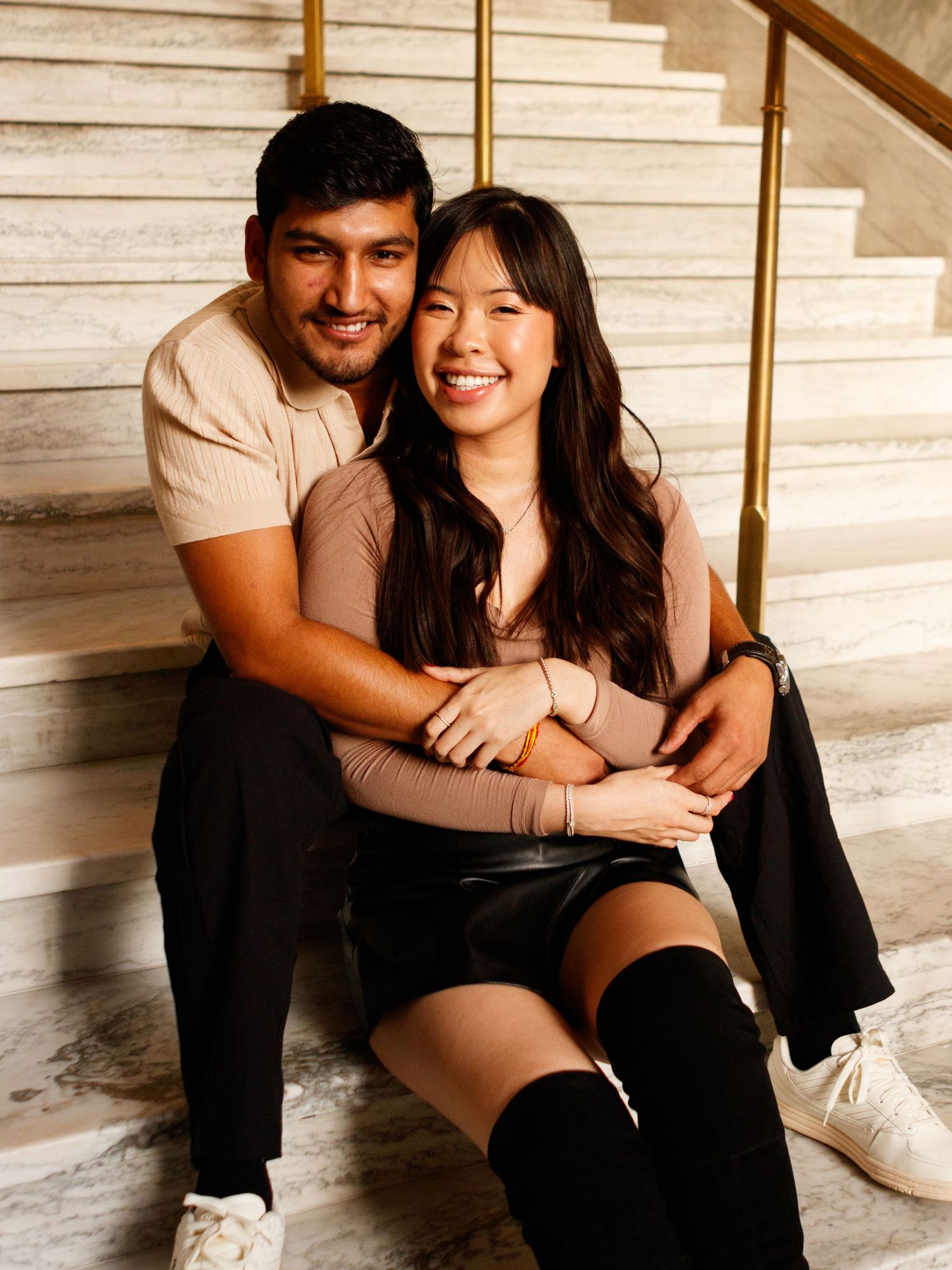 Couple sitting on steps with their arms wrapped around eachother.