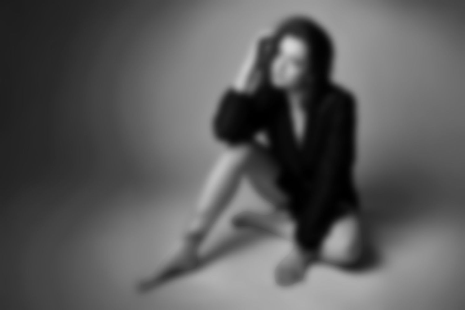 Black and white portrait of a woman in a blazer sitting on the floor.