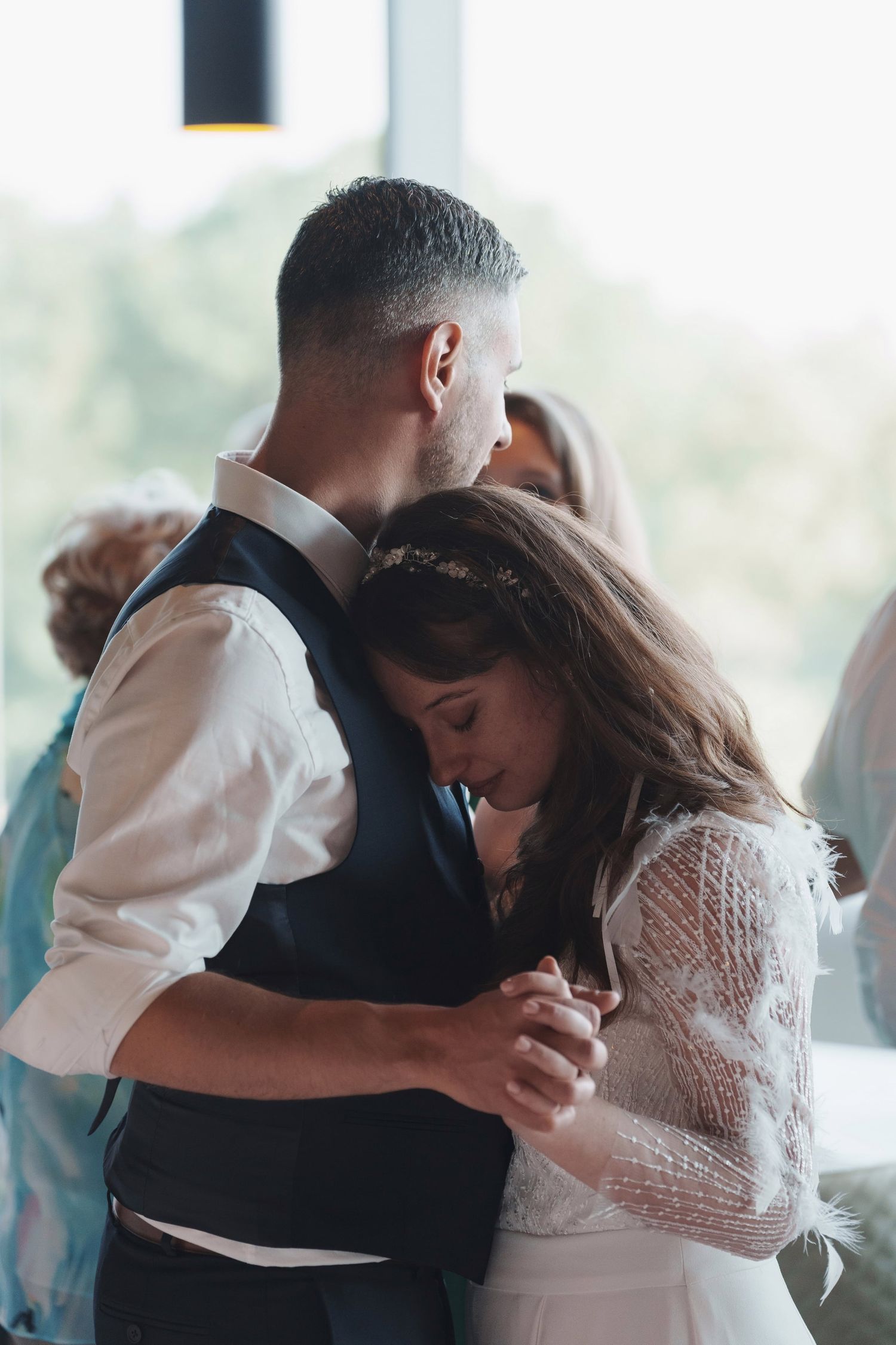 Bride and groom share an intimate first dance, bride resting her head on grooms chest.